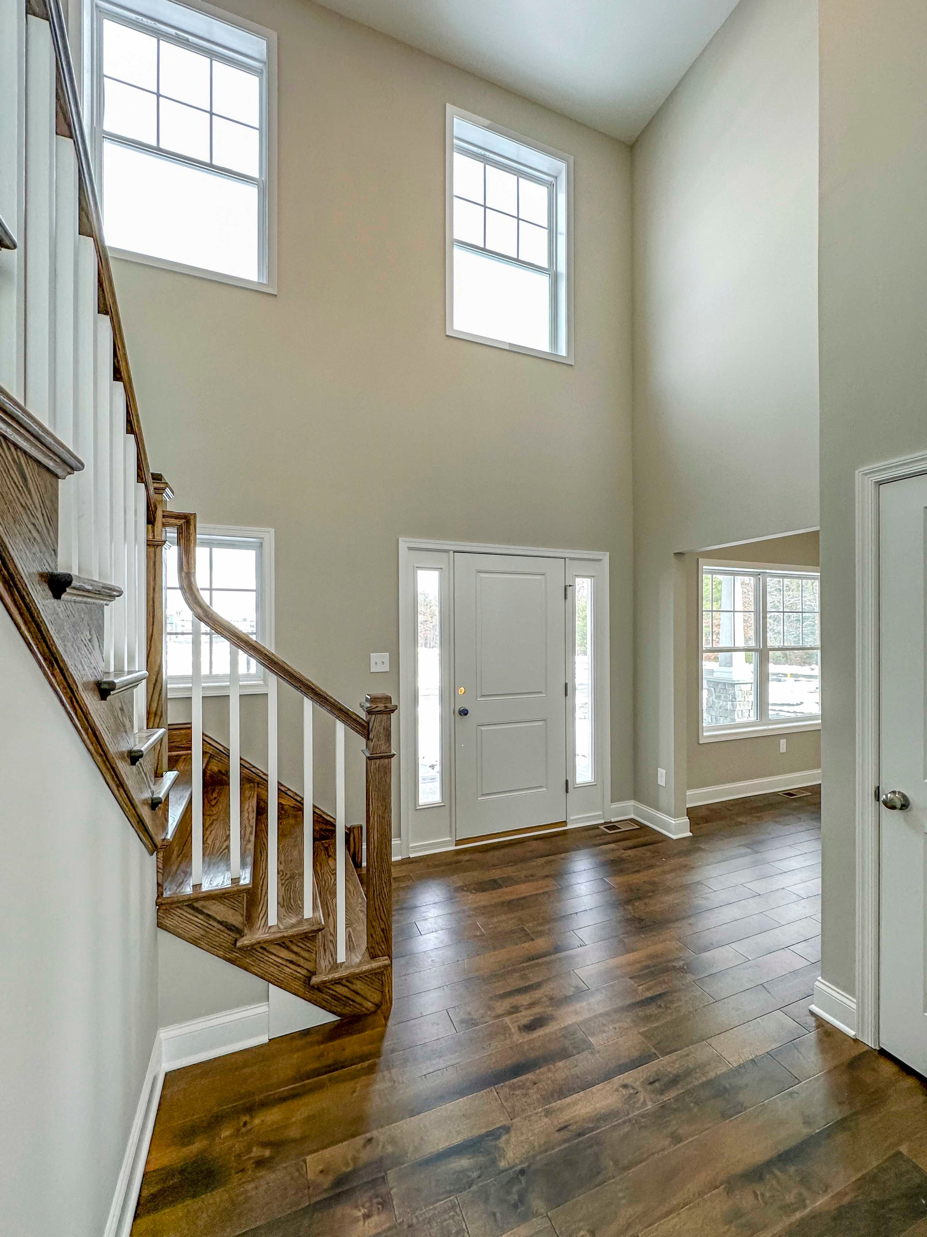 Foyer - Front door with staircase to second floor on left, entryway to formal dining room to right of image, door to powder room in front right.