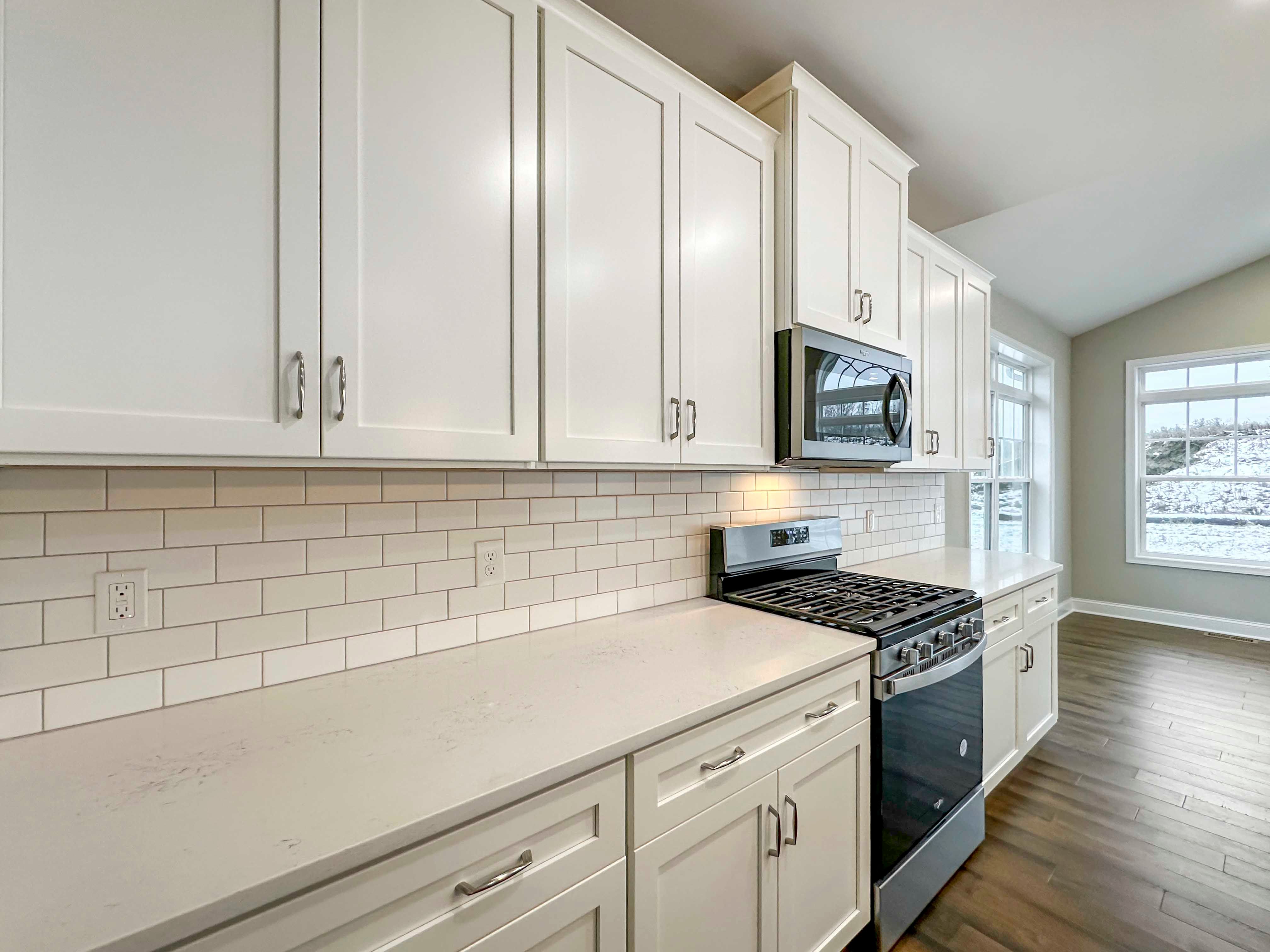 Kitchen - with white cabinetry, ceramic tile backsplash, stainless appliances, quartz countertops, and Opt. Keeping Room to right.