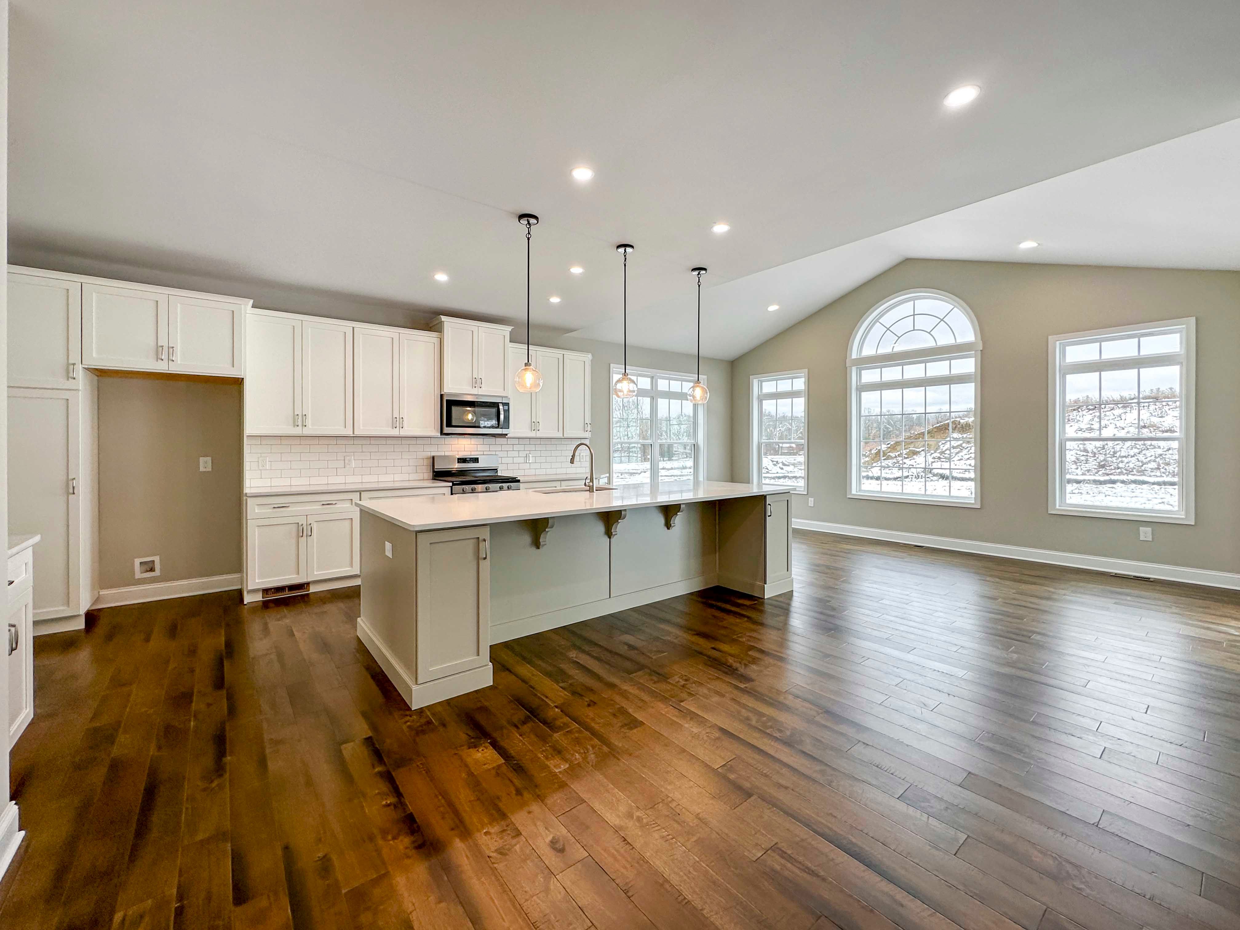 Kitchen - Island with overhang, white cabinetry, and hardwood floor - Opt. Keeping Room to right.
