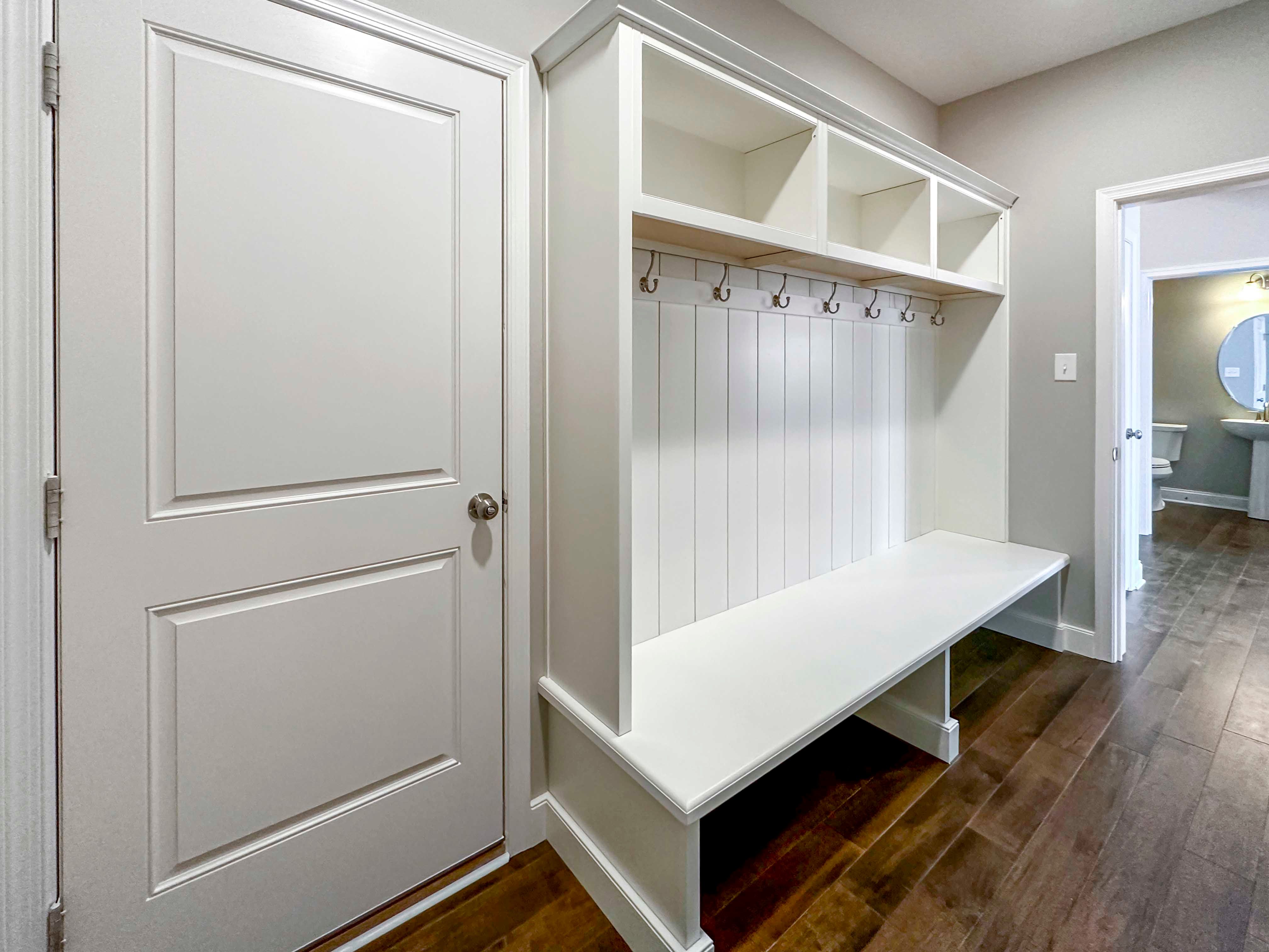 Mud Room - Door to Garage on left and bench with shelving and hooks to right.