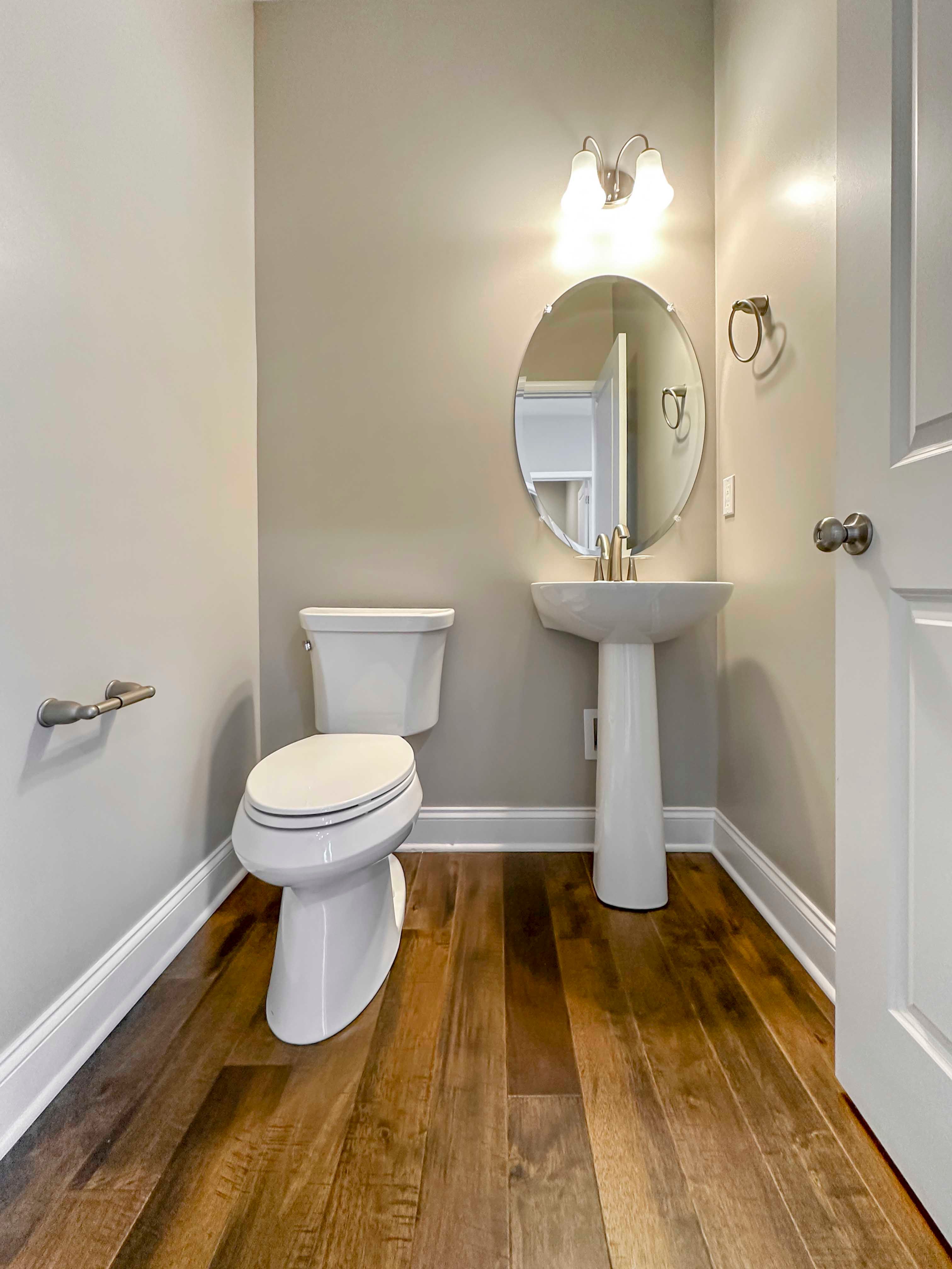 Powder Room - Pedestal sink with oval mirror to right and toilet to left