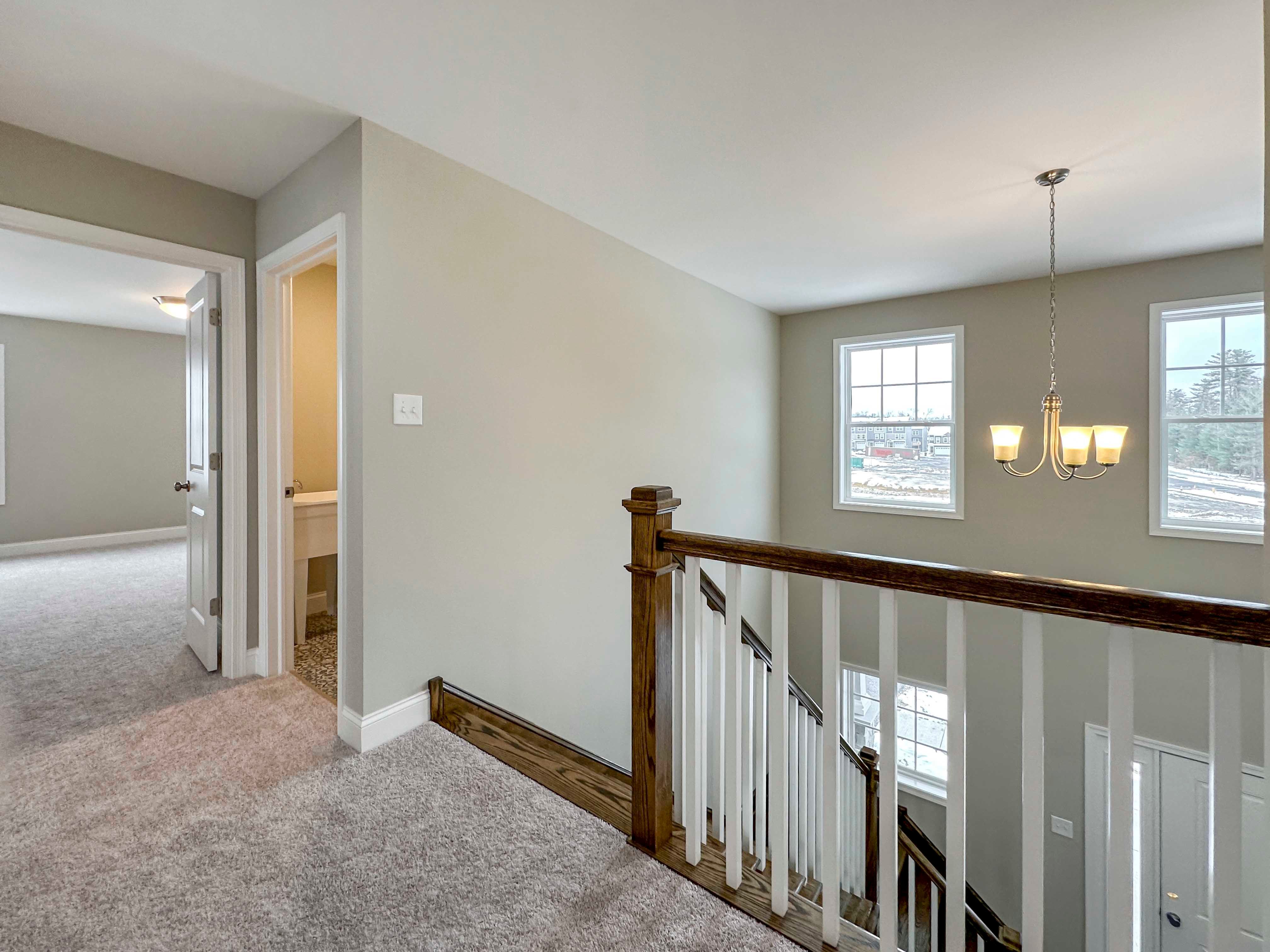 Landing of Second Floor - entryway to Laundry Room immediately to right of staircase, two windows at front wall, railing overlooks Foyer