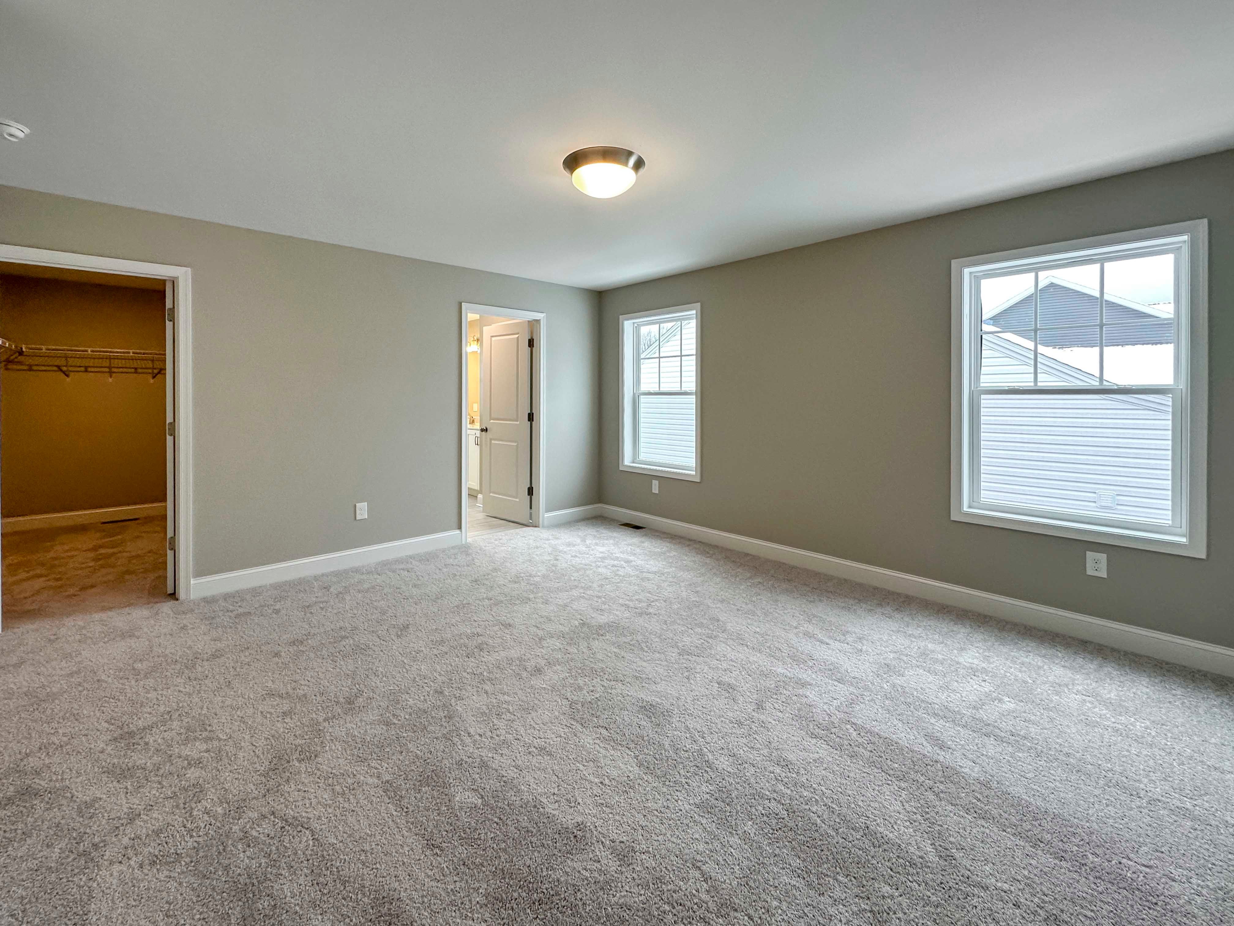 Owner's Bedroom - First door on left is walk-in closet, door on right is Owner's Bathroom. Two single-hung windows on wall to right.