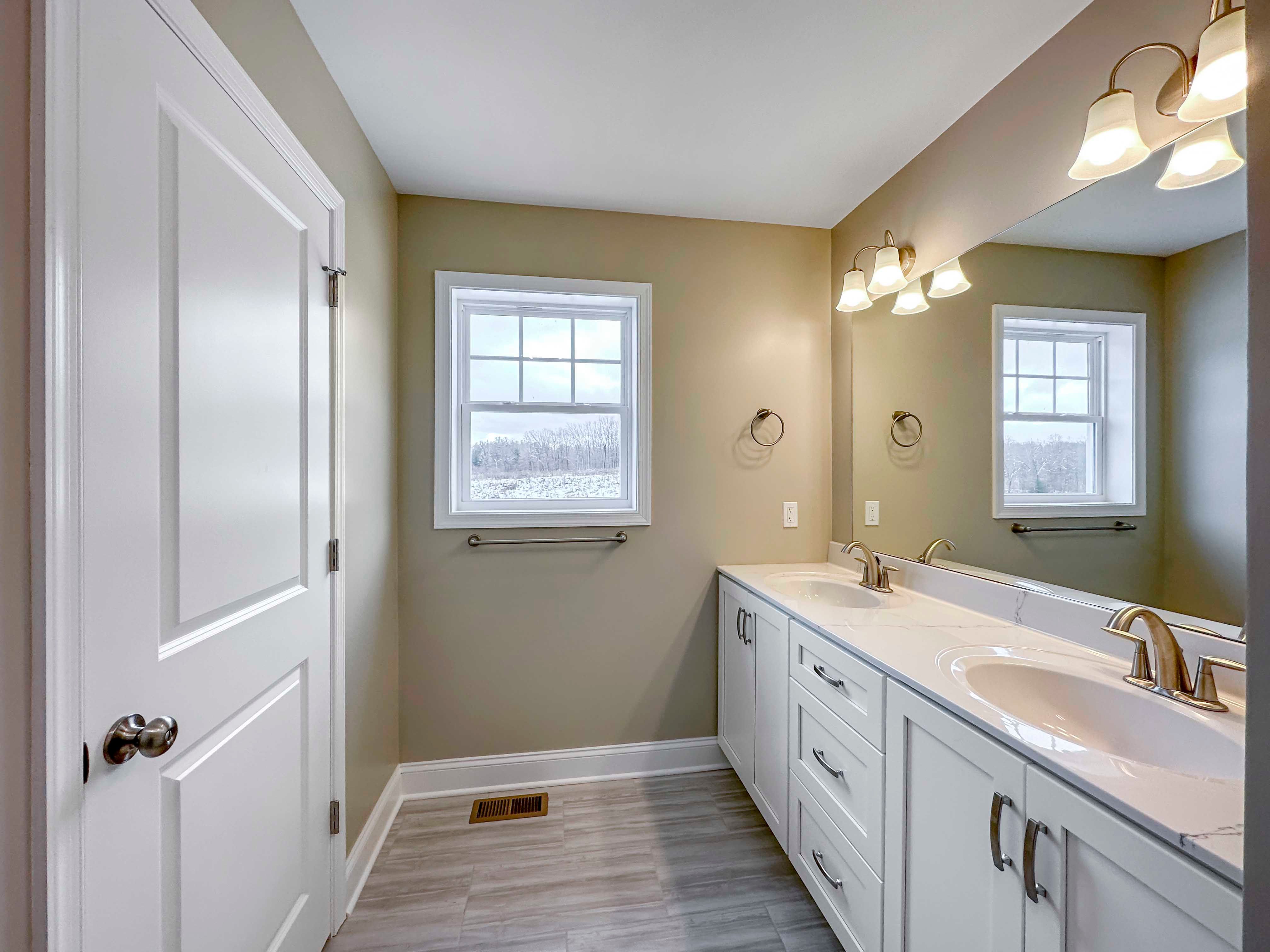 Owner's Bathroom - Double vanity with white cabinetry, single window, door to private water closet, large mirror above vanity.