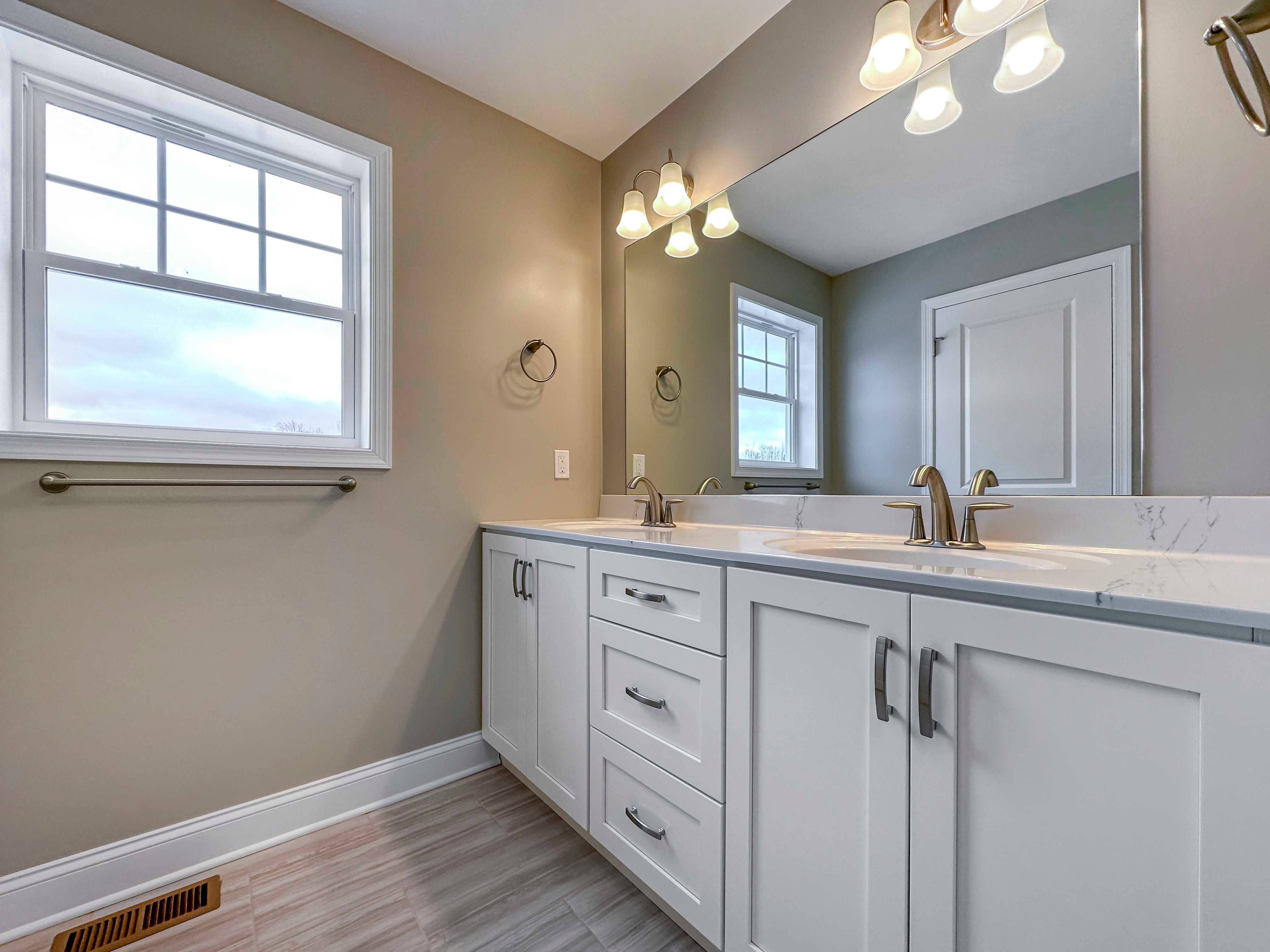 Owner's Bathroom - White cabinetry, double vanity, large mirror, single window.