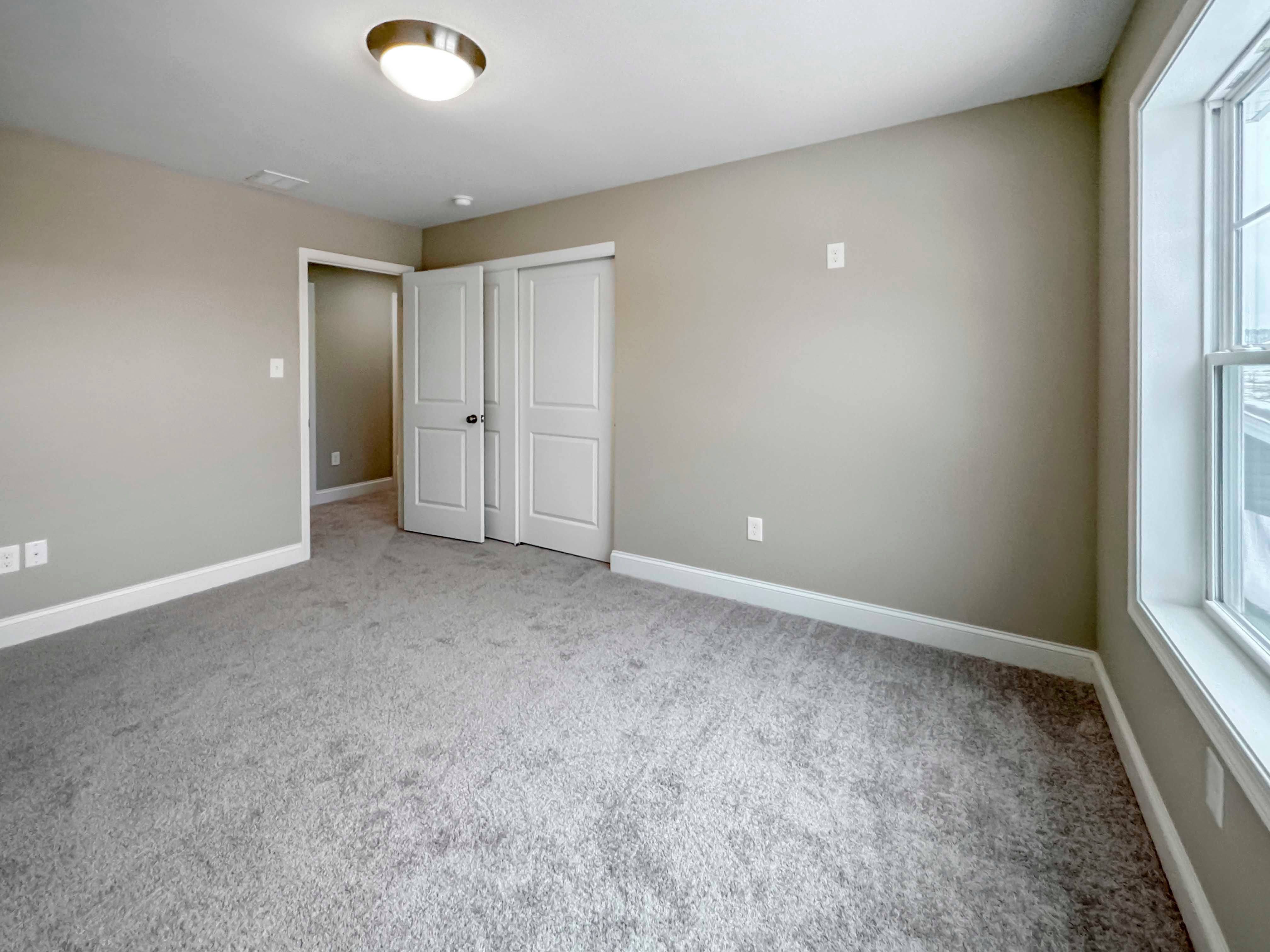 Bedroom 2 - Entrance on left side, window on right side, carpet flooring.