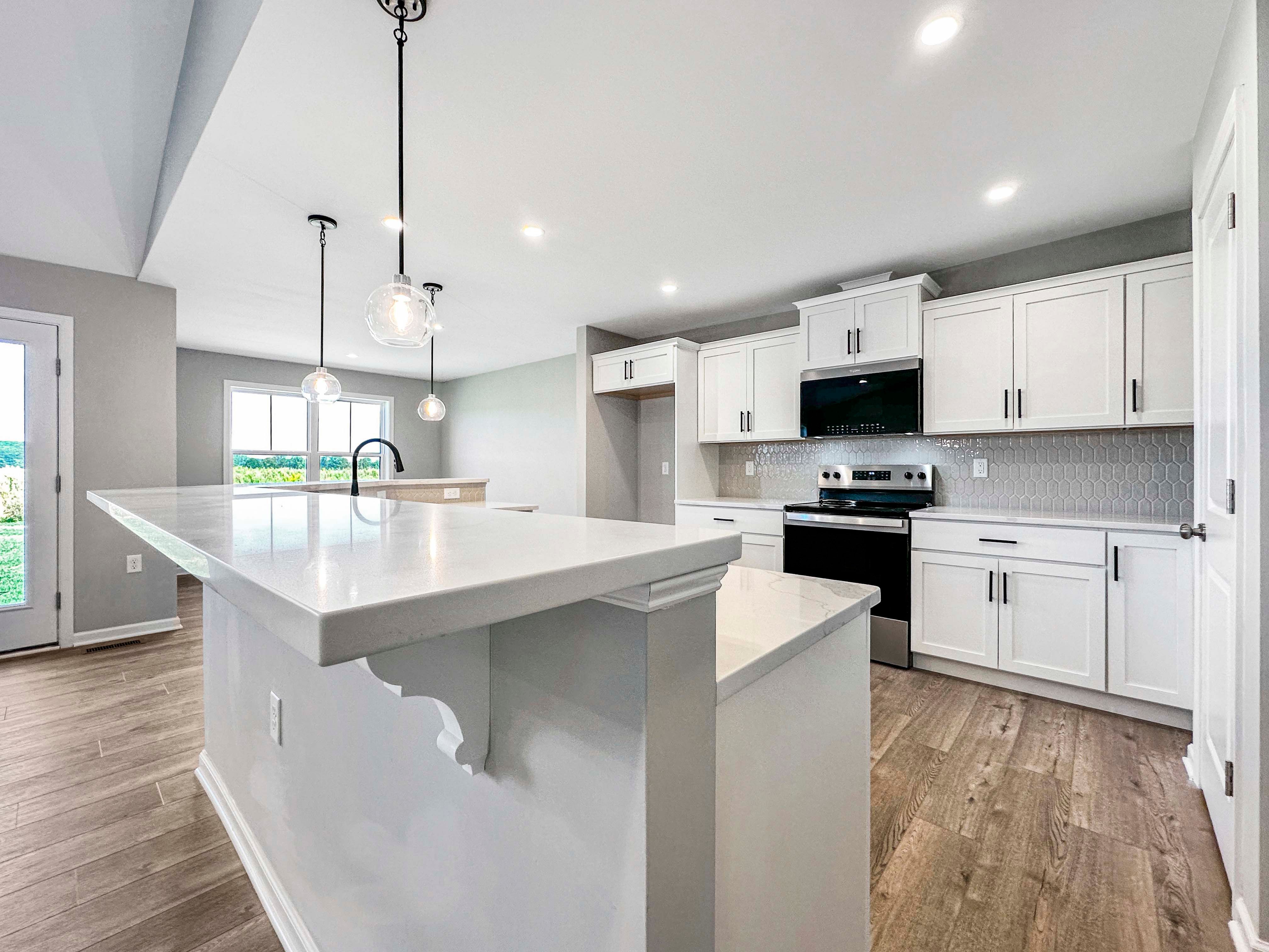 Modern kitchen with white quartz countertops, a stainless steel range, and ample cabinetry. Hexagonal tile backsplash adds a contemporary touch.