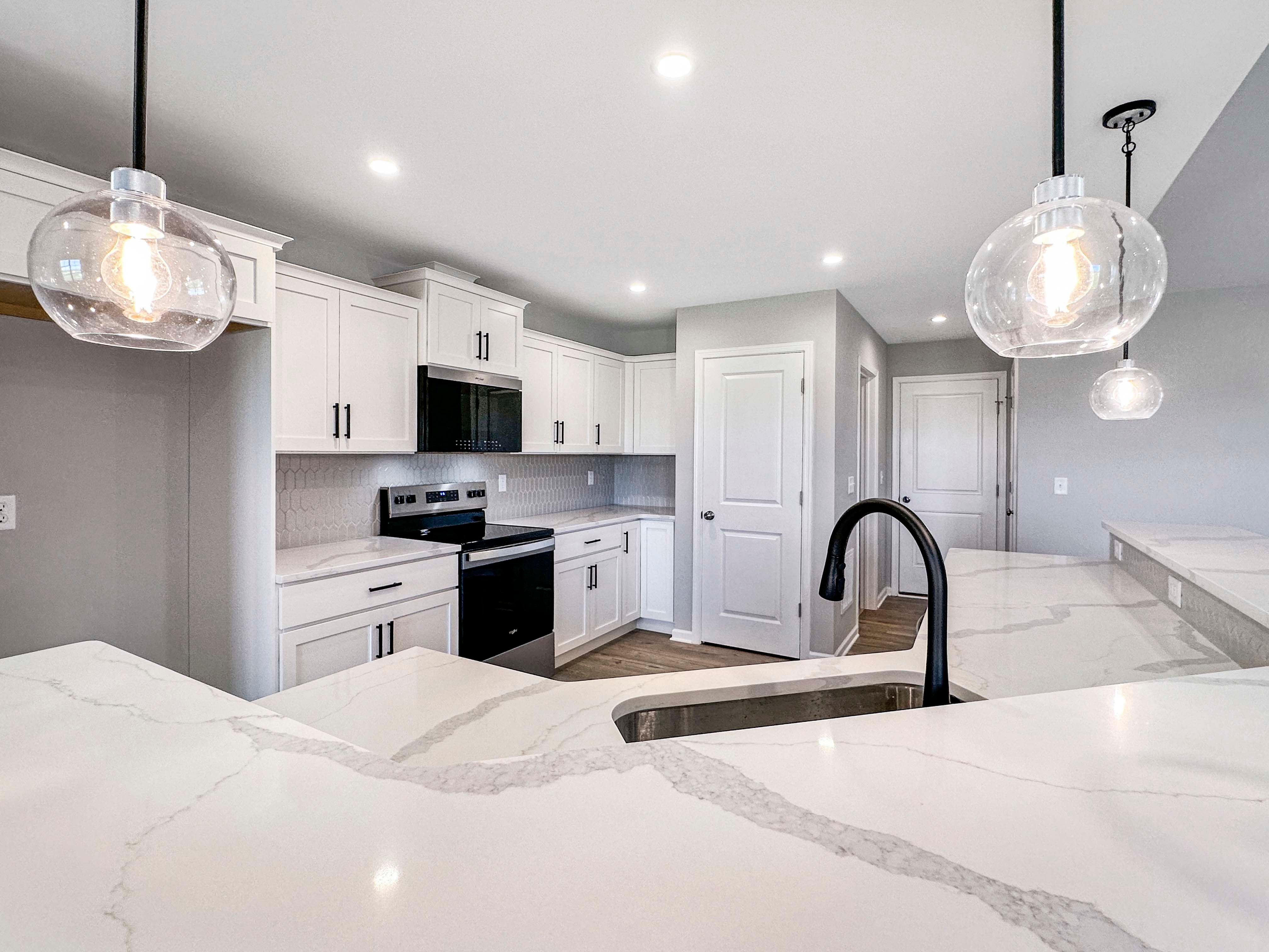 Sleek kitchen island with white quartz countertops and stainless steel sink. Pendant lighting above adds a modern feel.