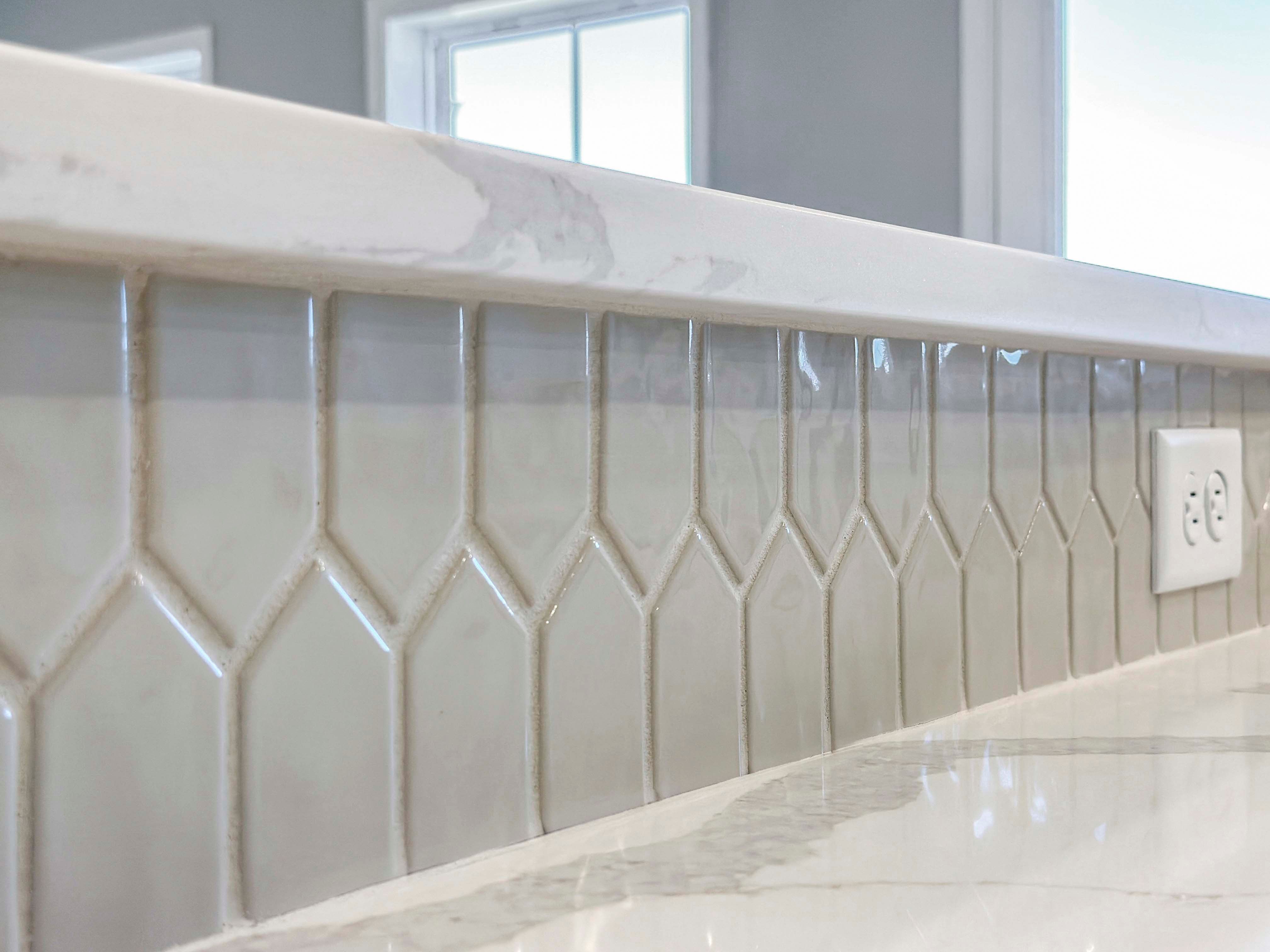 Wide view of a kitchen showcasing quartz countertops, black appliances, pendant lights, and a large island with ample workspace.