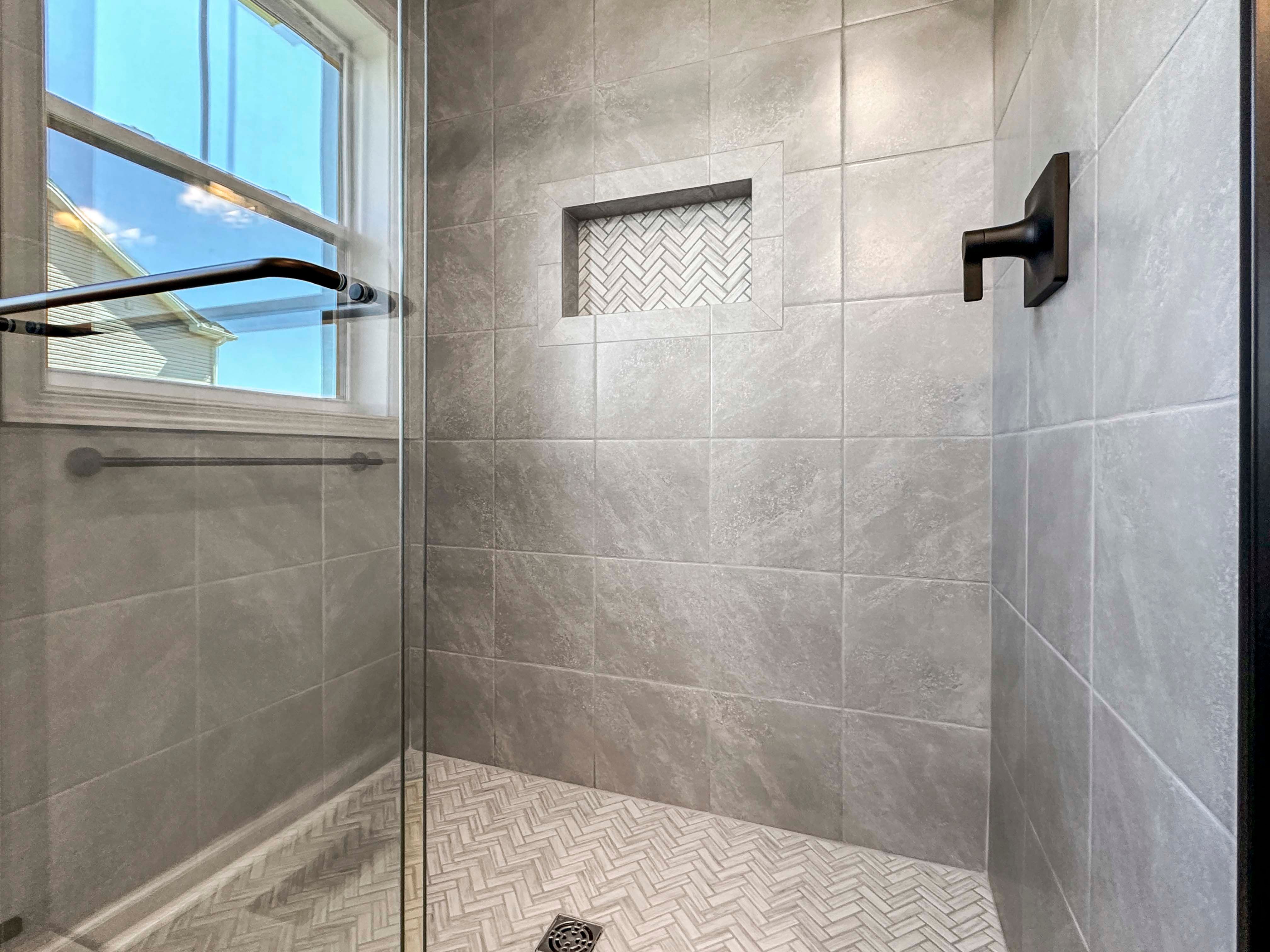Owners bath shower with reflection of a window in glass and decorative niche