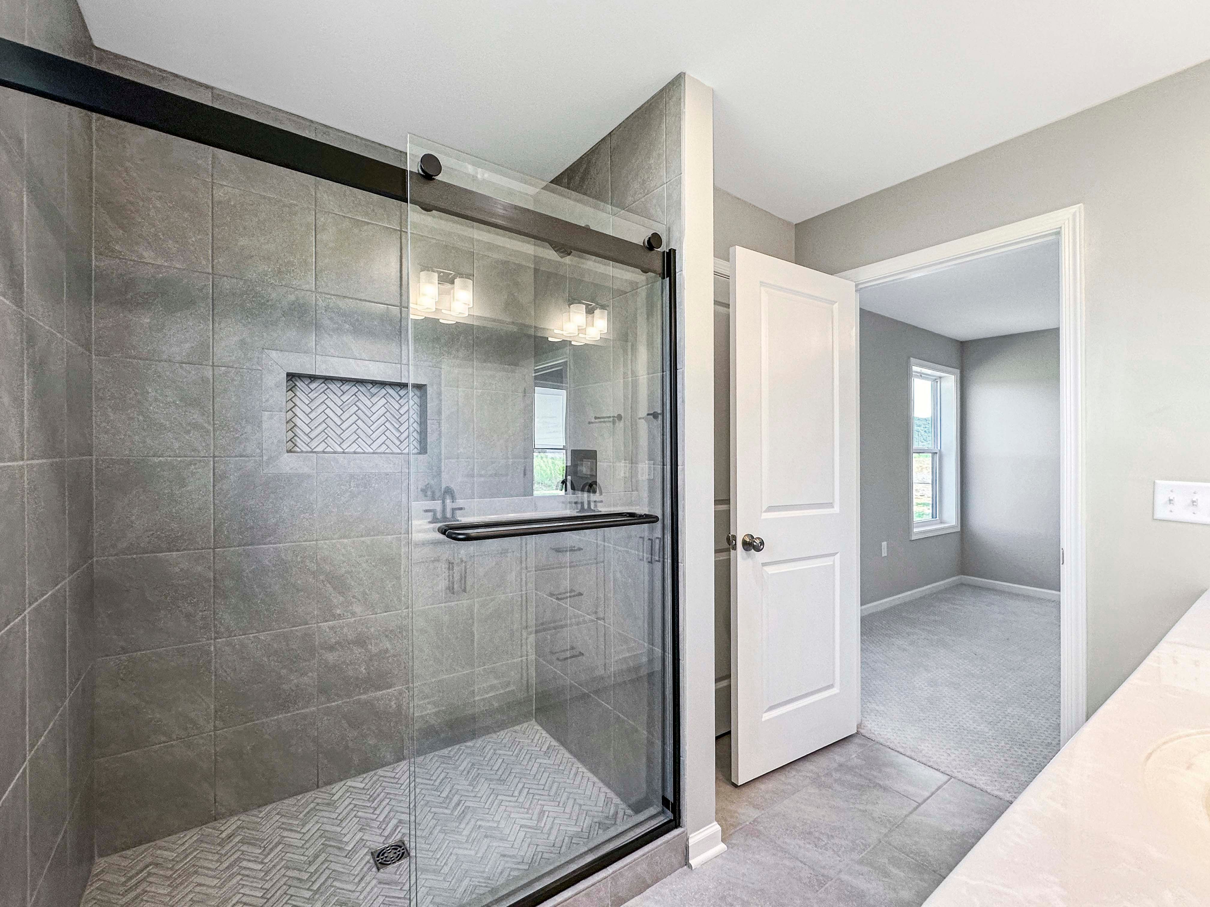 Owner's bathroom featuring a dual-sink vanity, black faucets, and two white doors leading to separate areas.