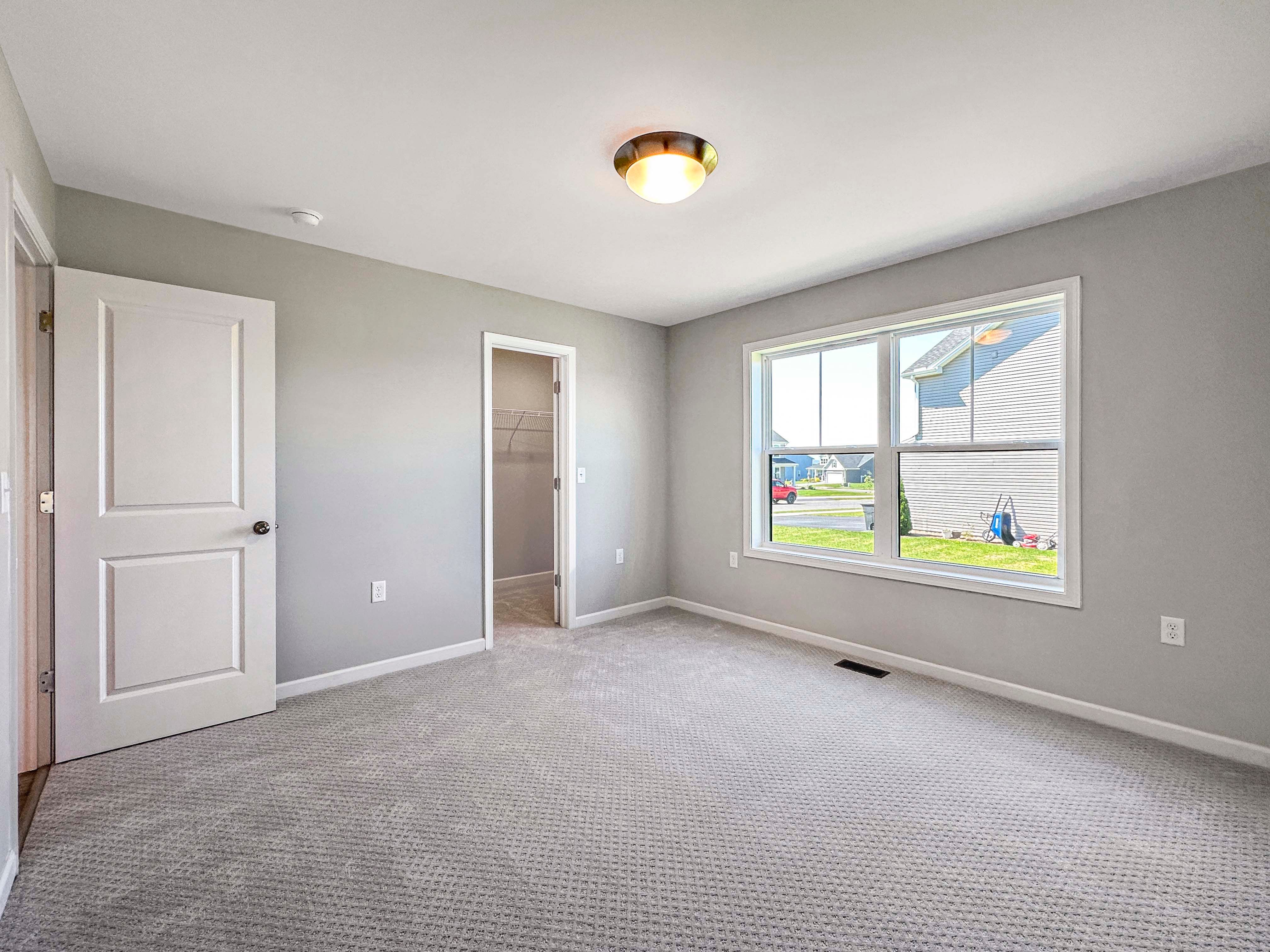 Unfurnished bedroom with large windows, gray carpet, and neutral-colored walls.
