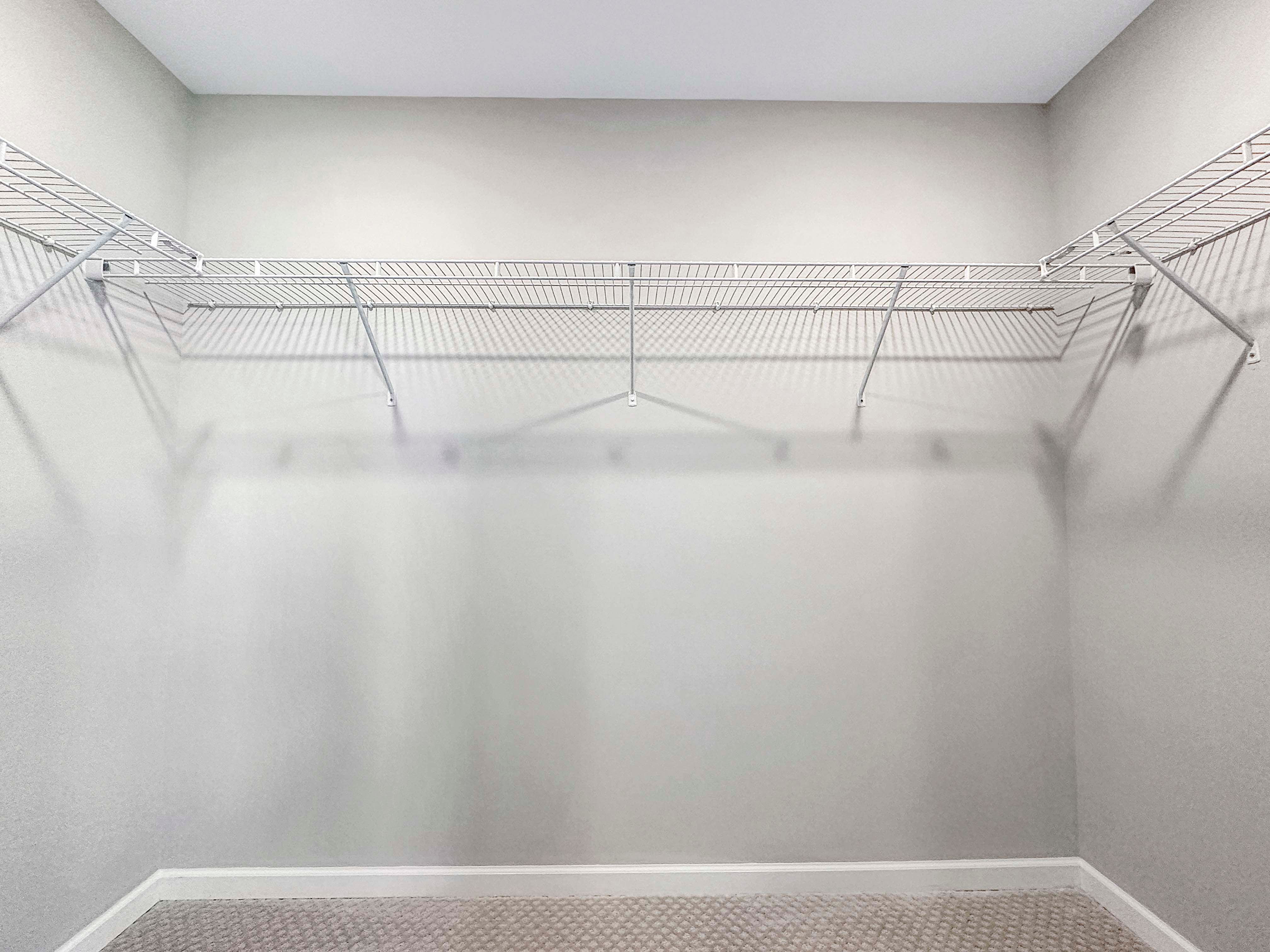 Walk-in closet with built-in wire shelving, gray carpet, and neutral wall tones.