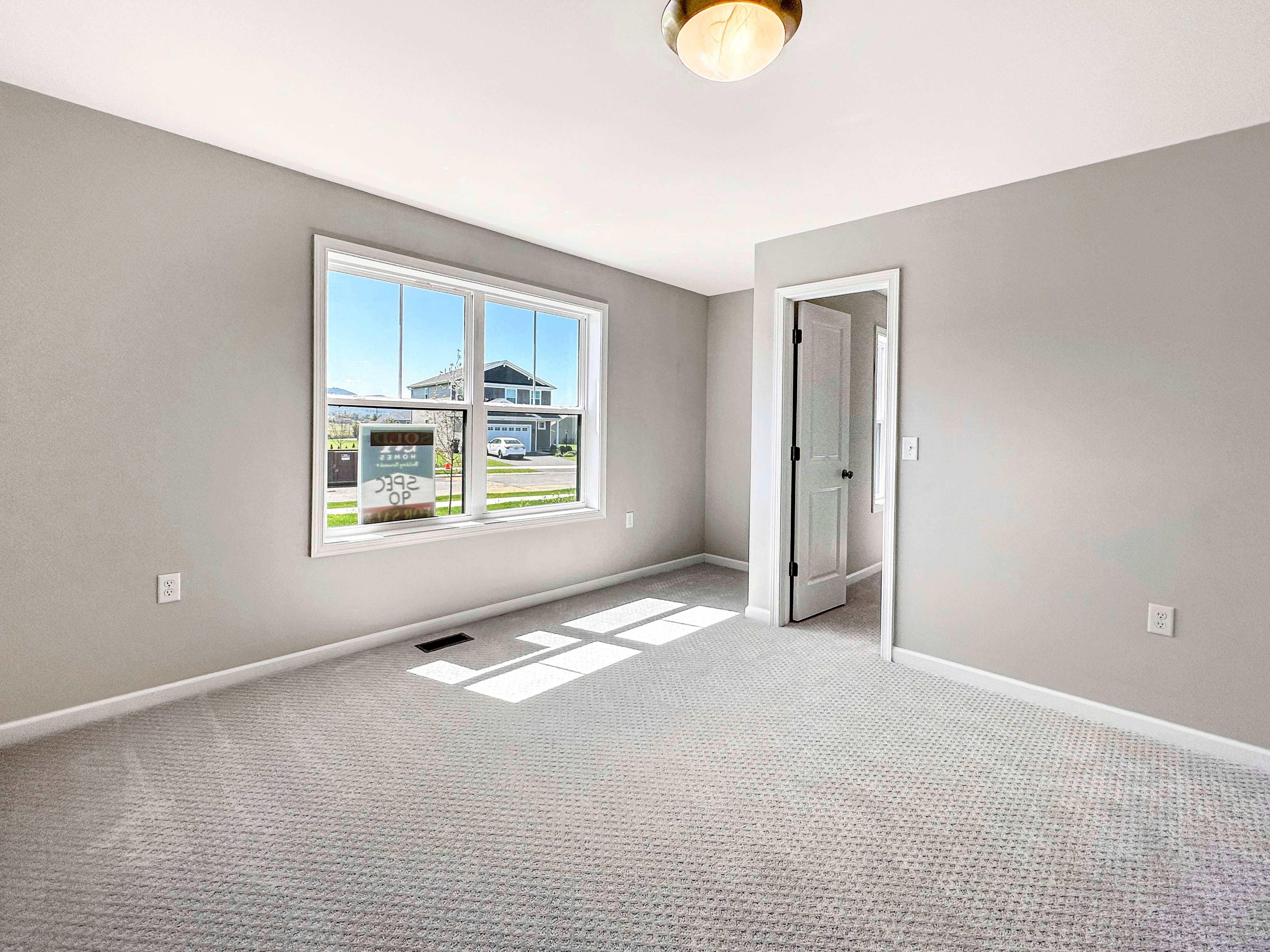 Unfurnished bedroom featuring a large window with a view of the neighborhood, gray carpet, and closet.