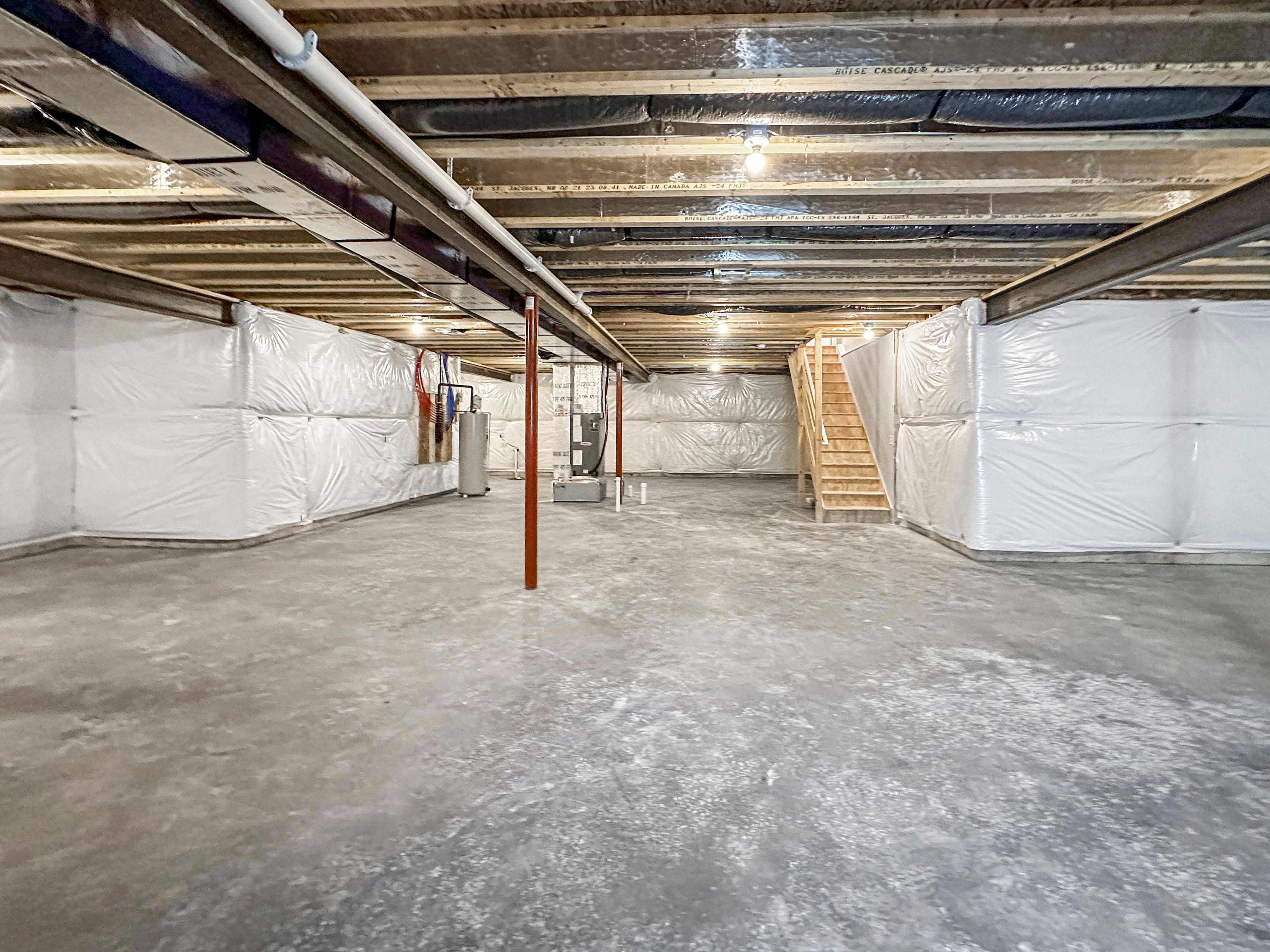 Unfurnished basement with concrete flooring, exposed beams, ductwork, and utility equipment. Stairs leading to the main level.