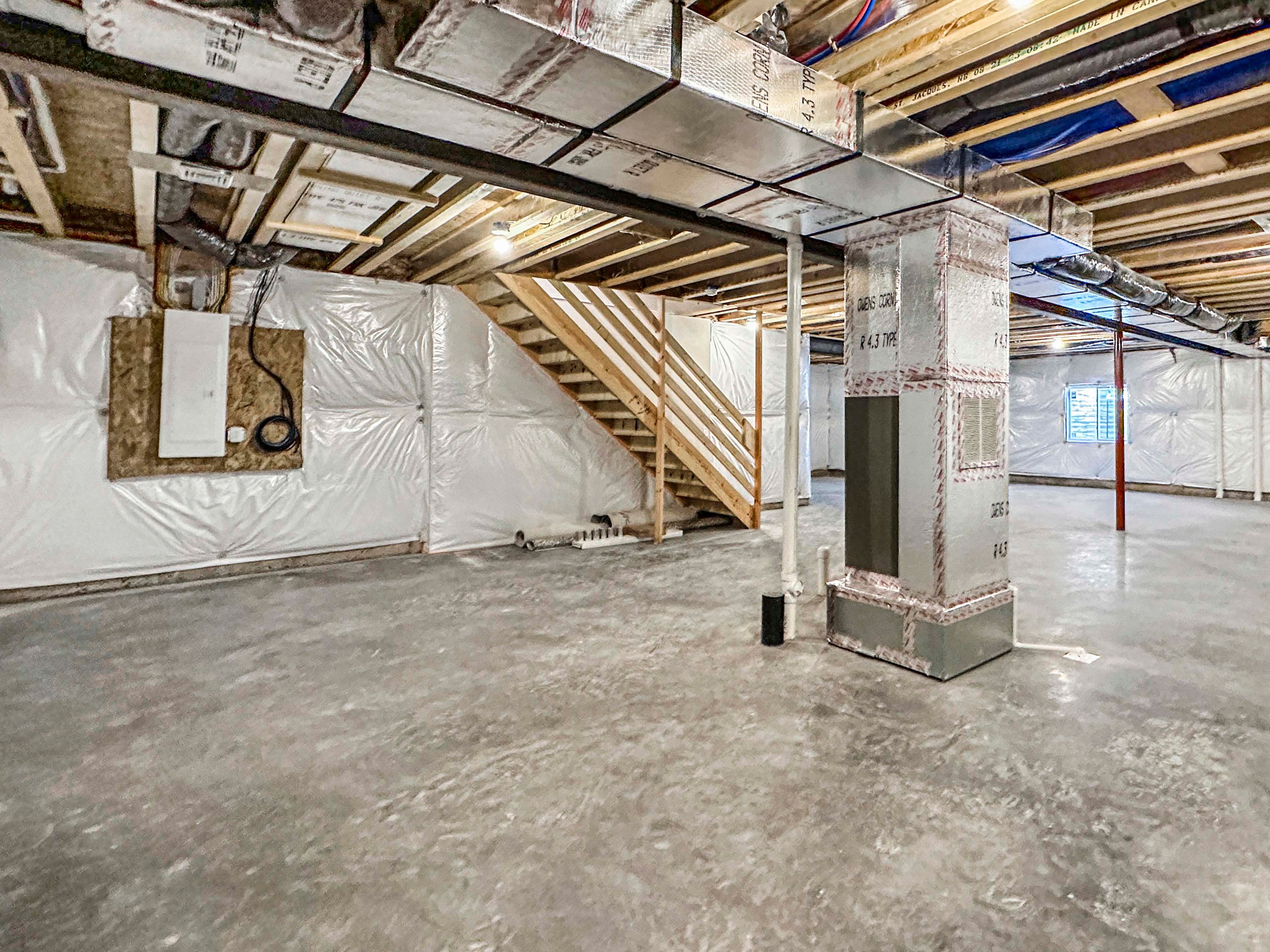 Basement with exposed ceiling beams, ductwork, and concrete flooring. Includes utility equipment and stairs leading up.