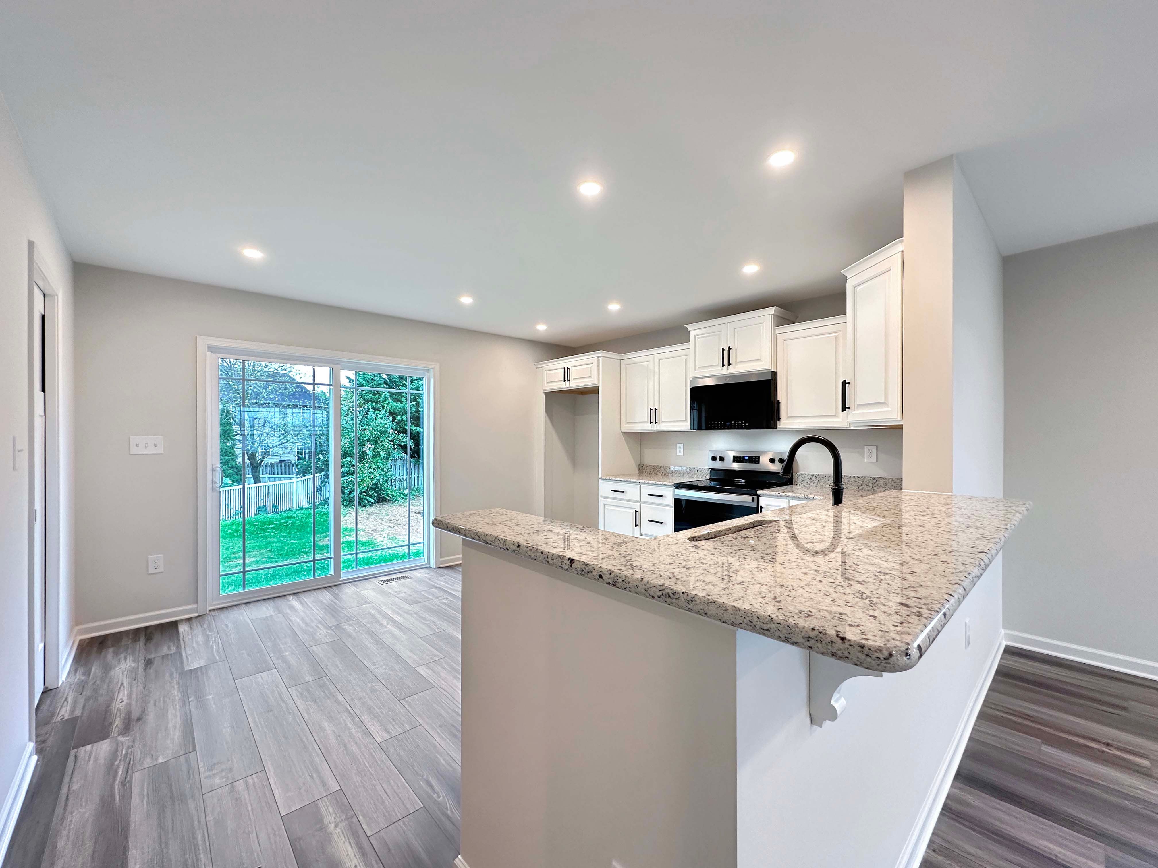 Kitchen with sliding glass doors to backyard and bar overhang into Living Room area.