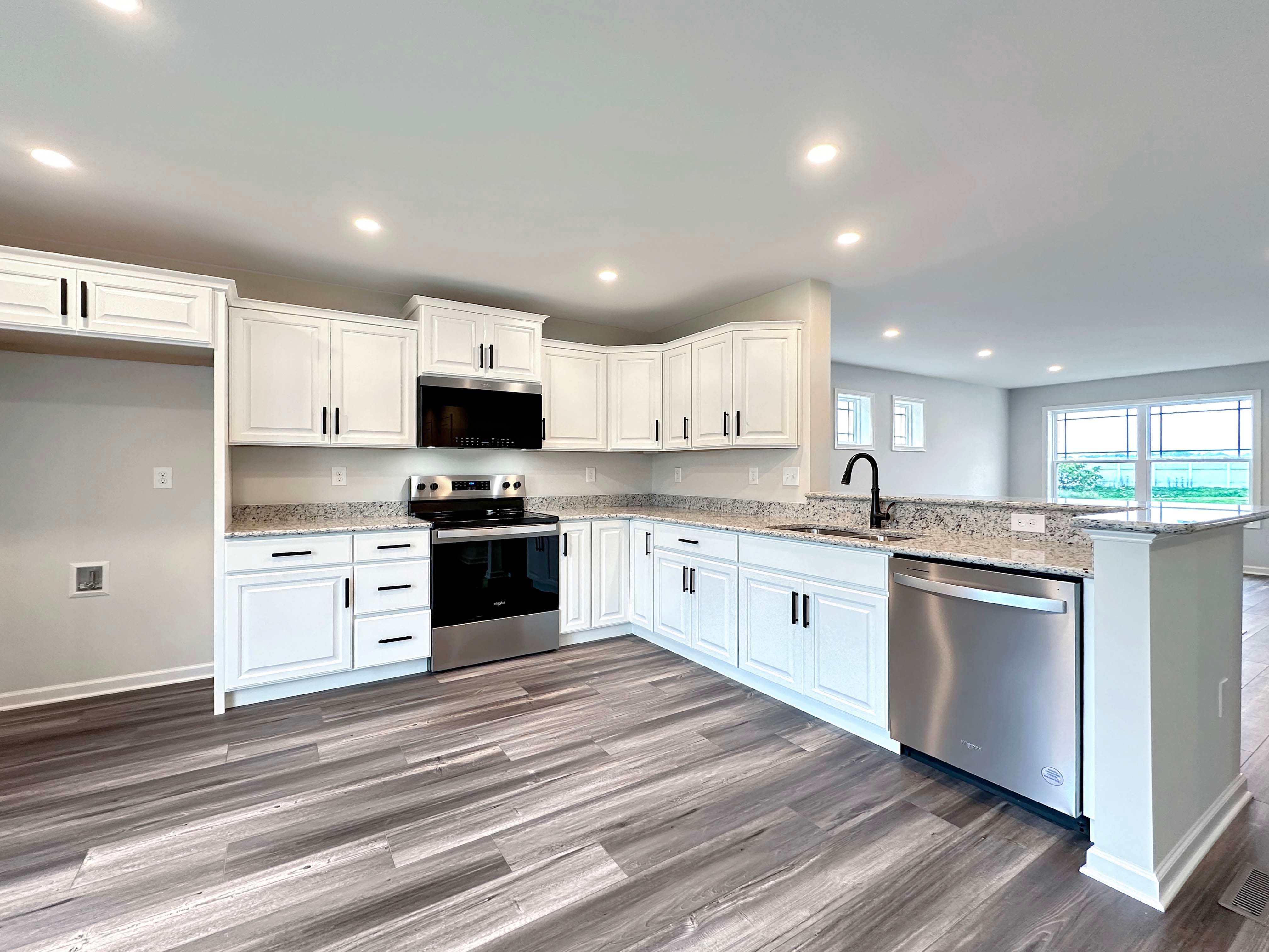 Kitchen with white cabinetry and stainless appliances, overlooking the Living Room area