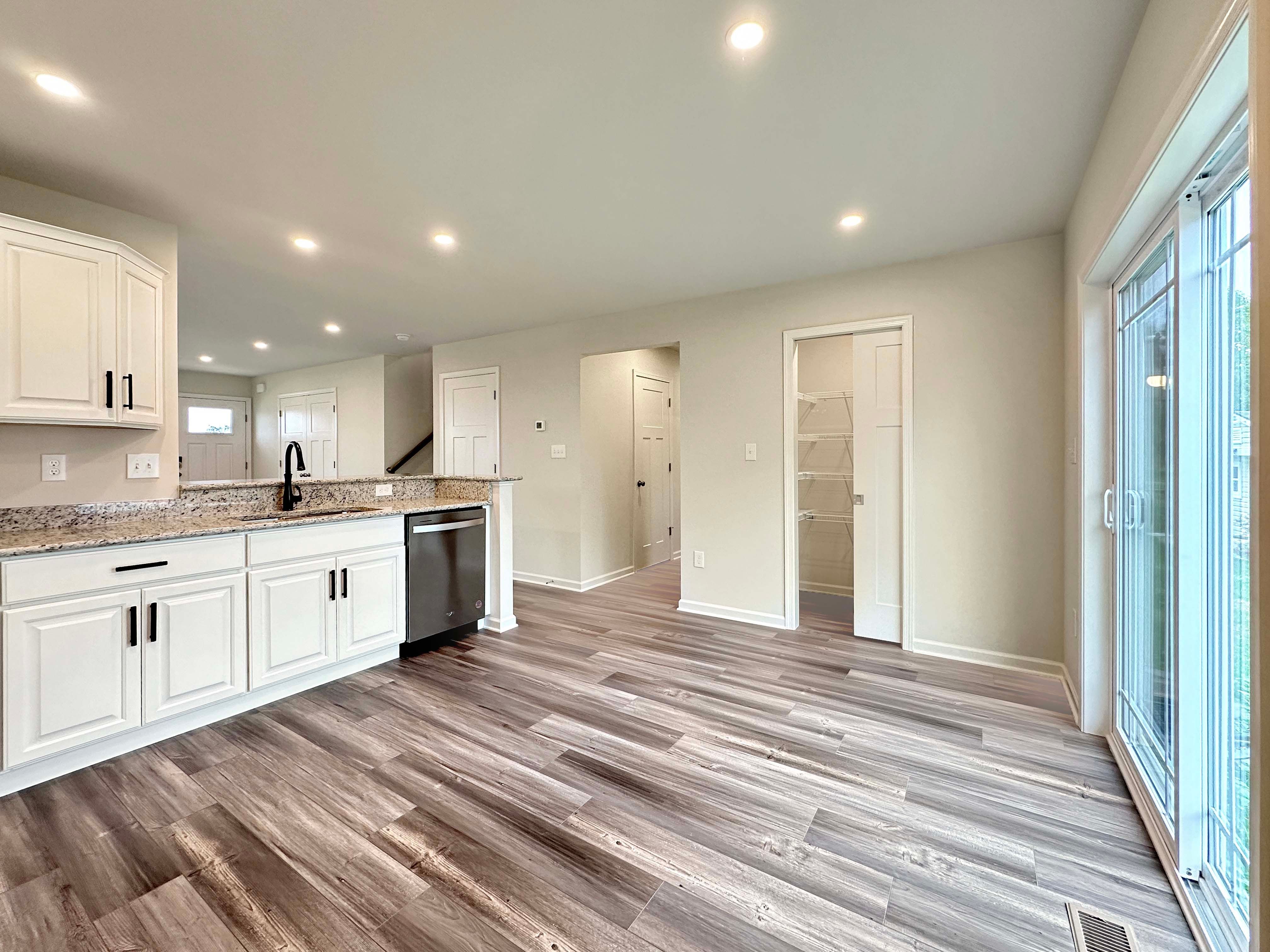 Modern kitchen with a large granite bar, white cabinetry, and a black faucet, overlooking a bright dining area with sliding doors