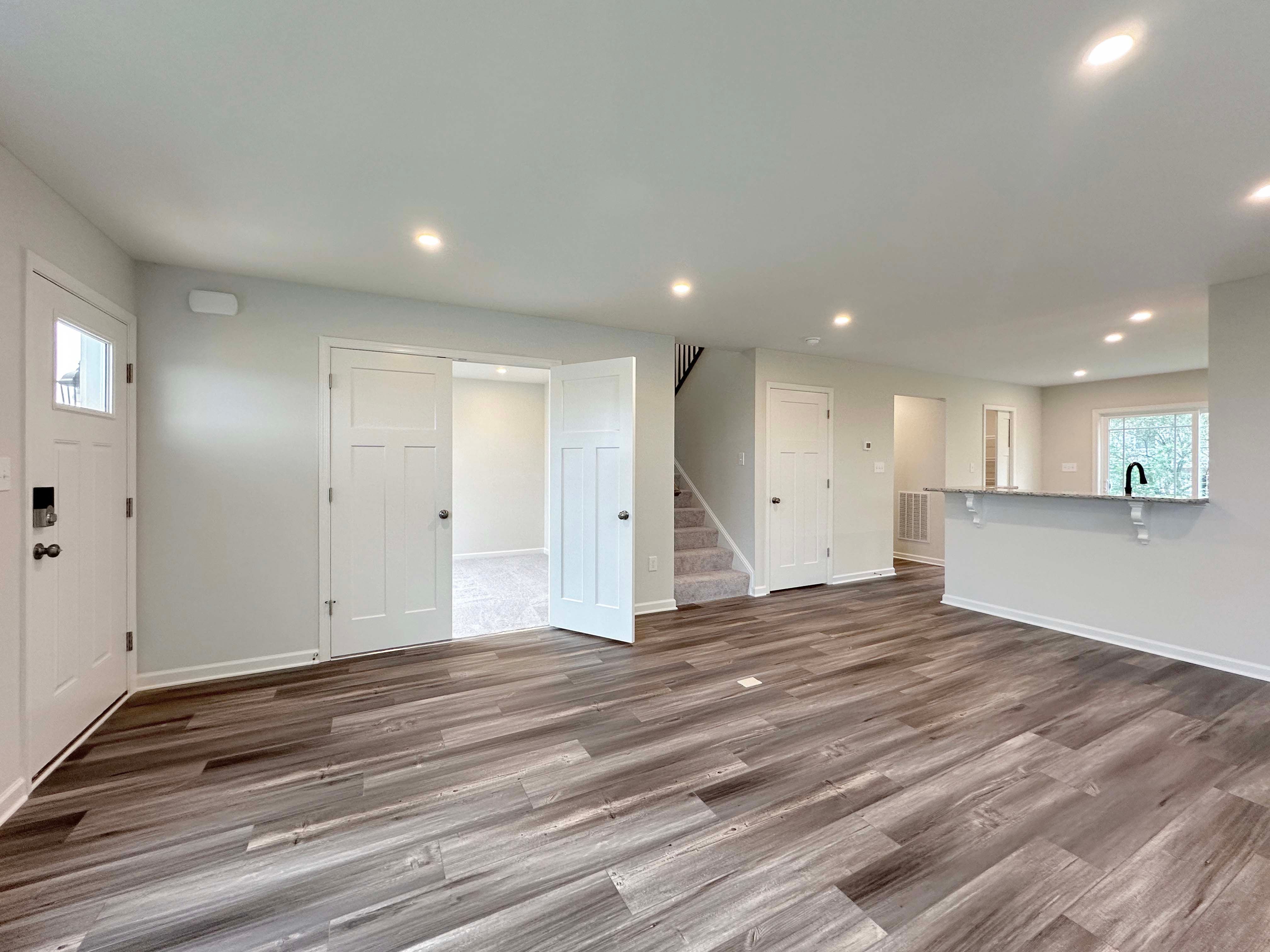 Unfurnished living room featuring a large window, recessed lighting, and modern wood-look floors.