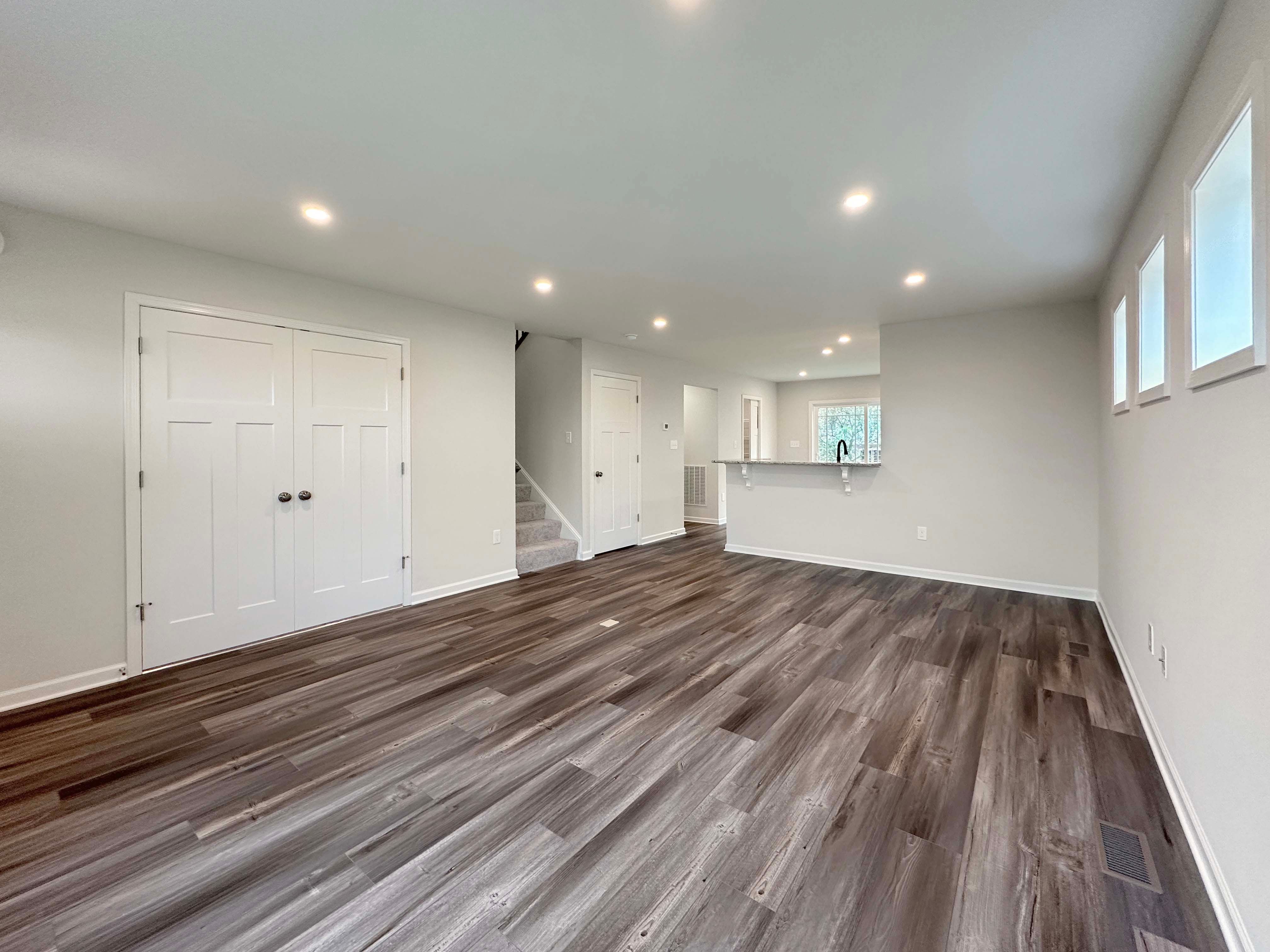 Unfurnished living room with open layout, modern flooring, recessed lighting, and staircase leading upstairs.