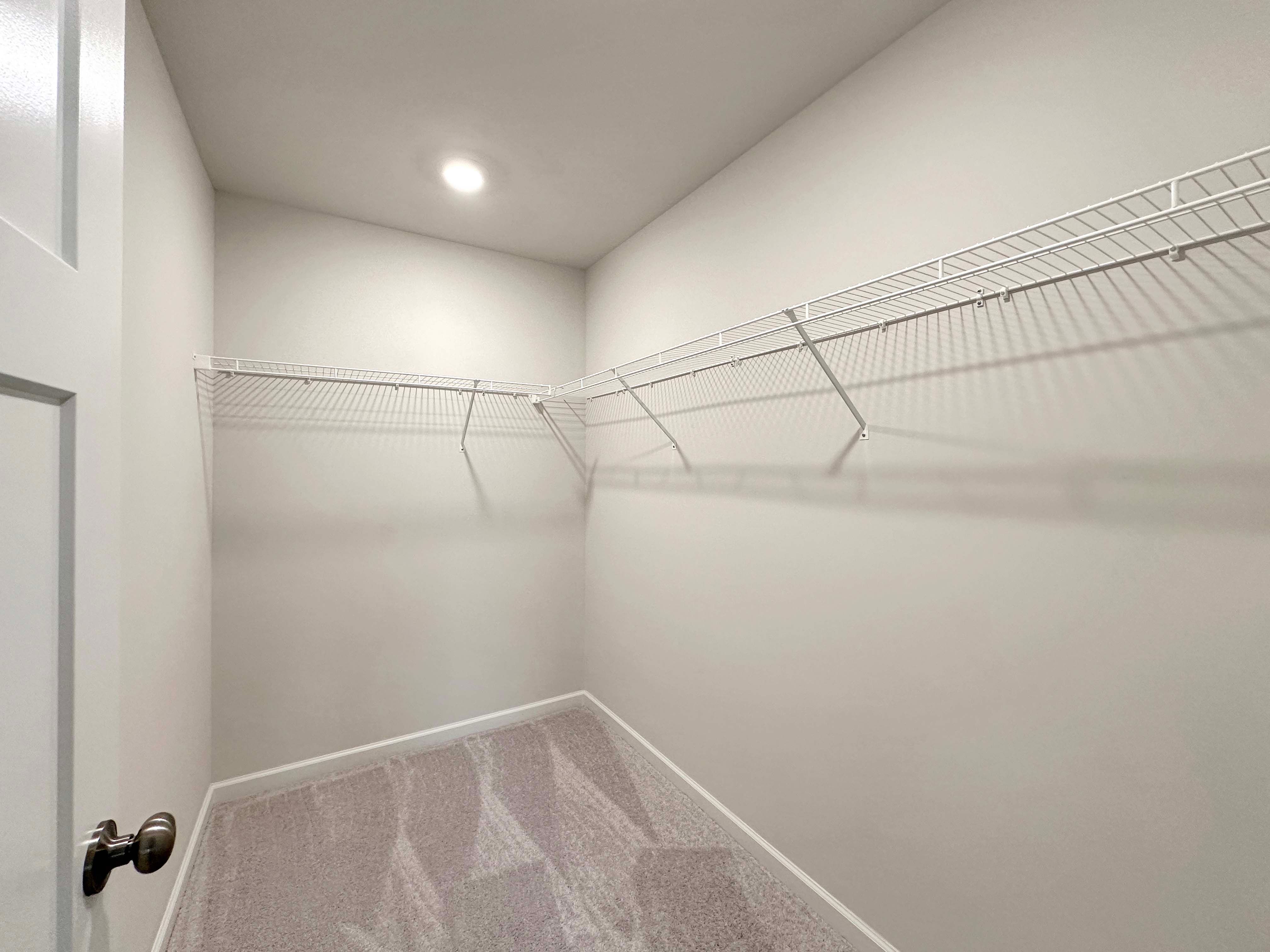 Walk-in closet in the owner's bedroom with wire shelving and overhead lighting