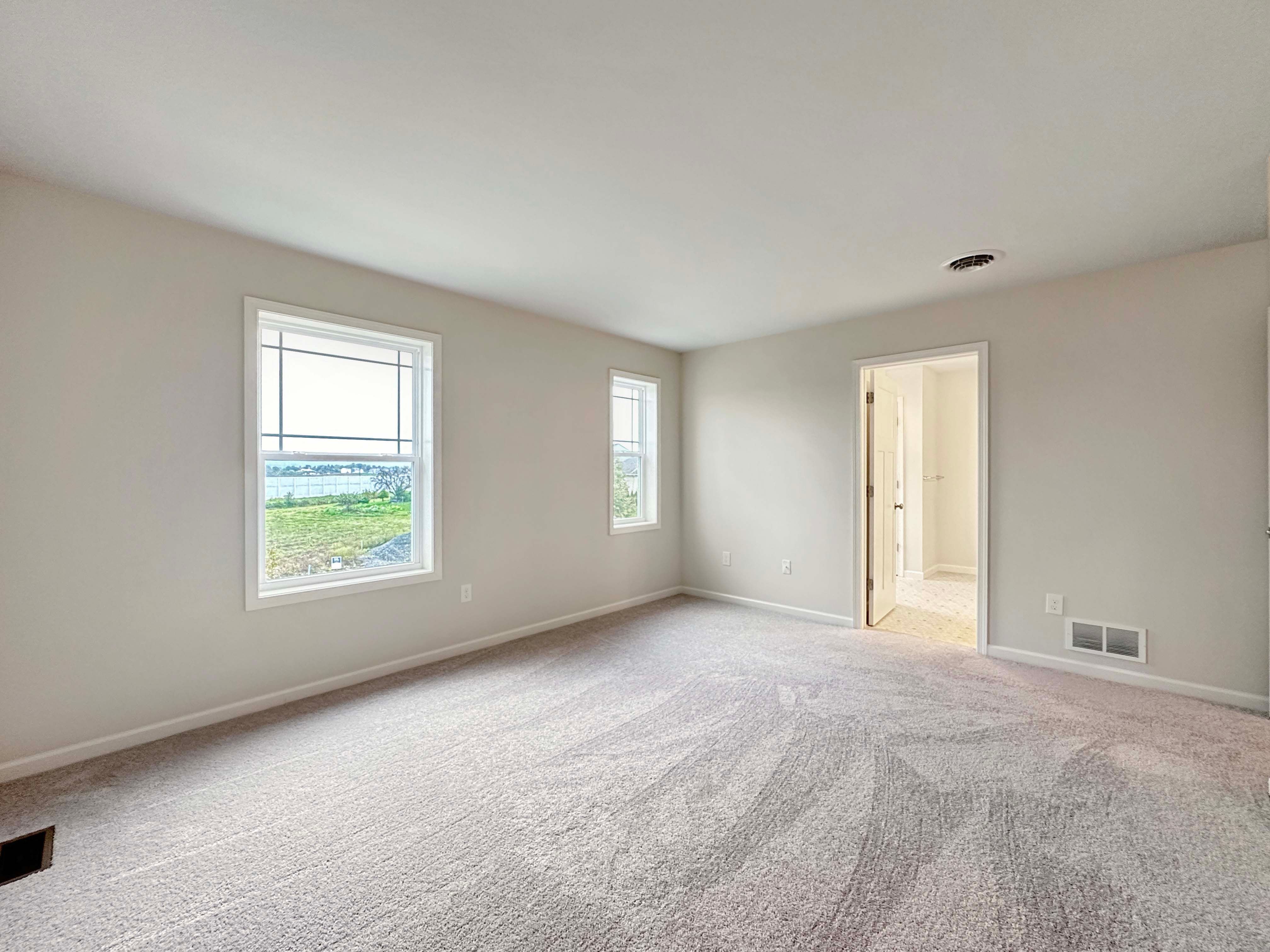 View of the owner's bedroom with carpet and open door leading to closet