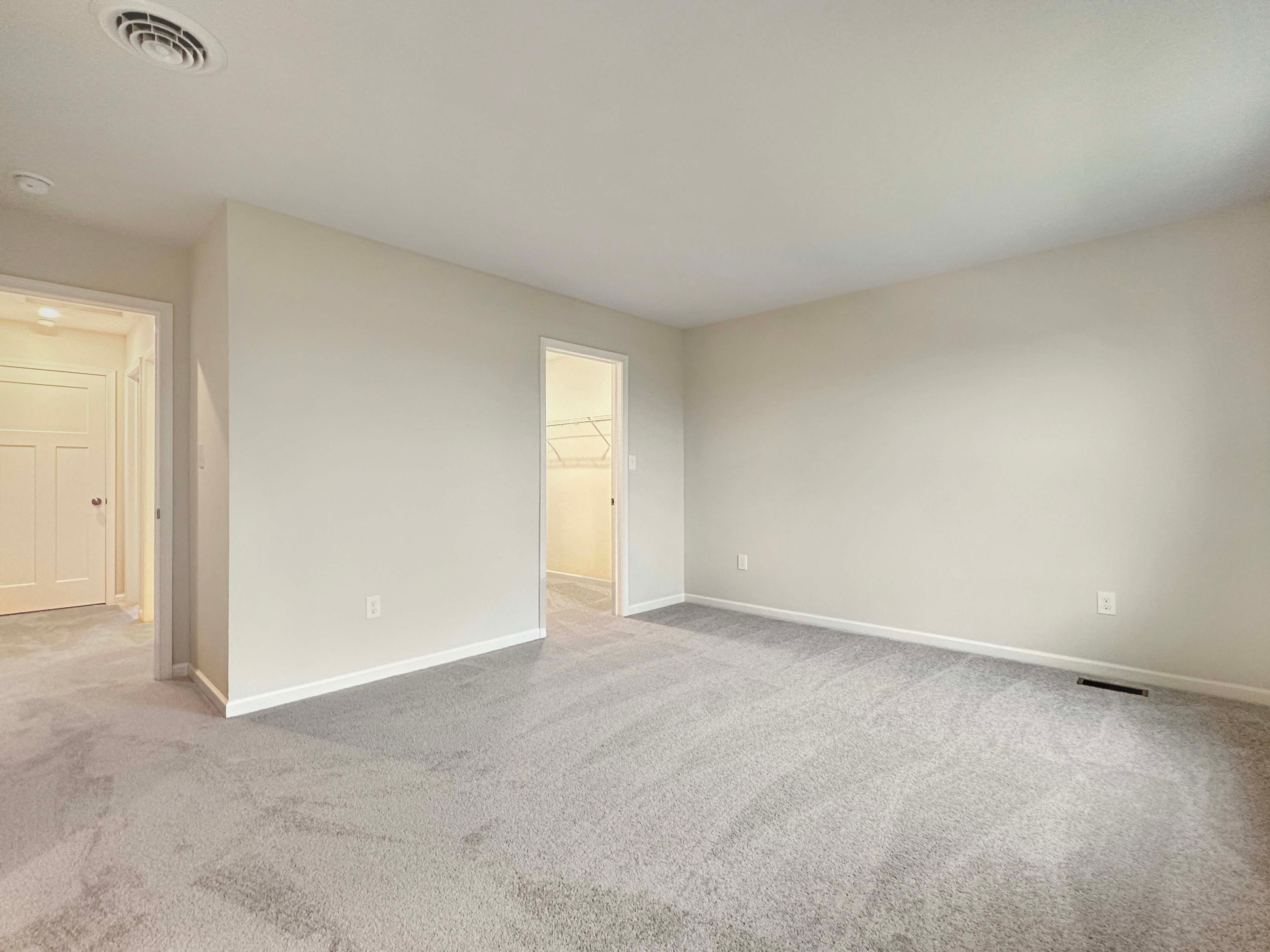 Bright owner's bedroom with two large windows and neutral walls