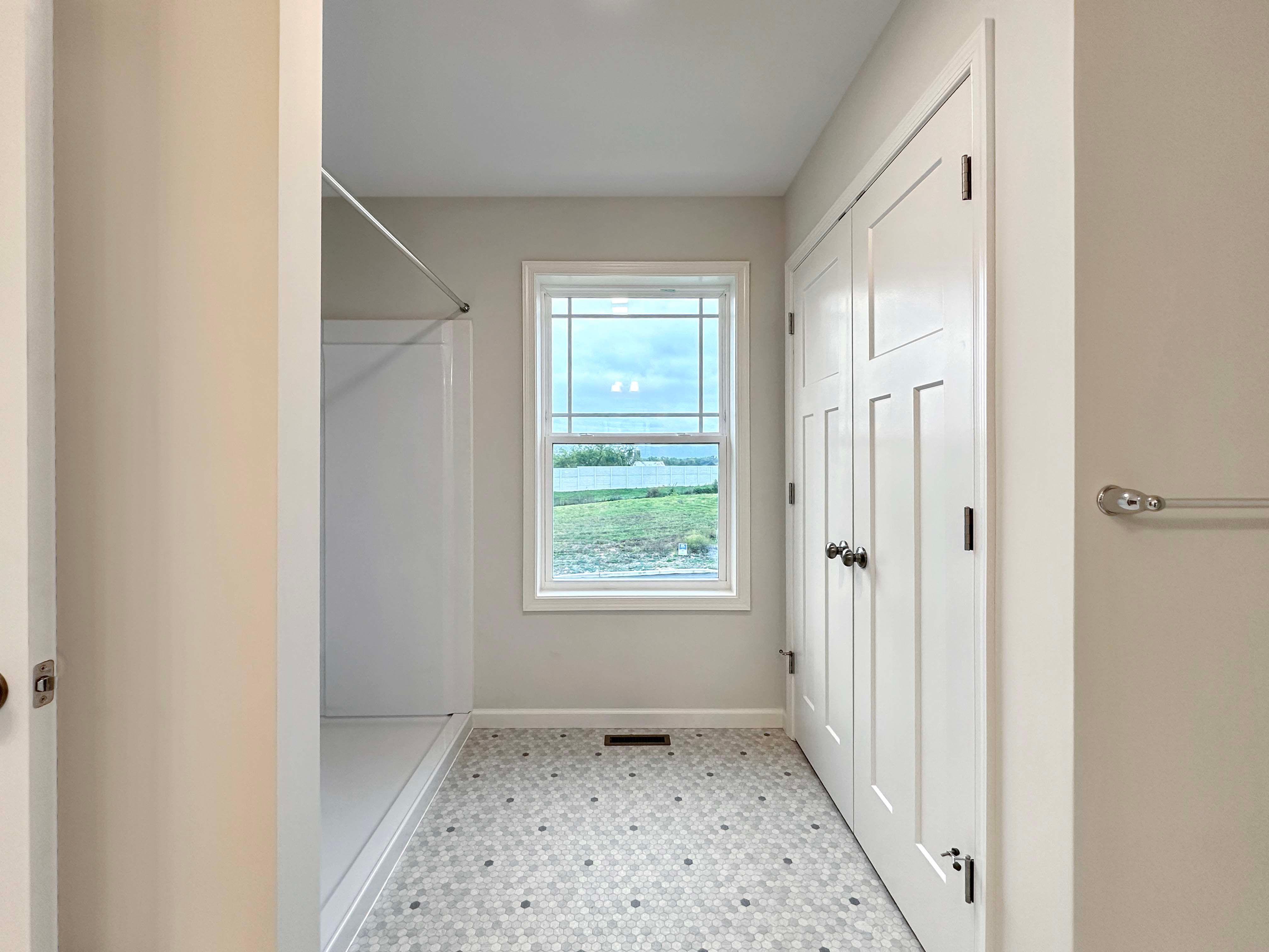 Owner's bathroom featuring a spacious linen closet, hexagon-tiled floor, and window for extra natural light.