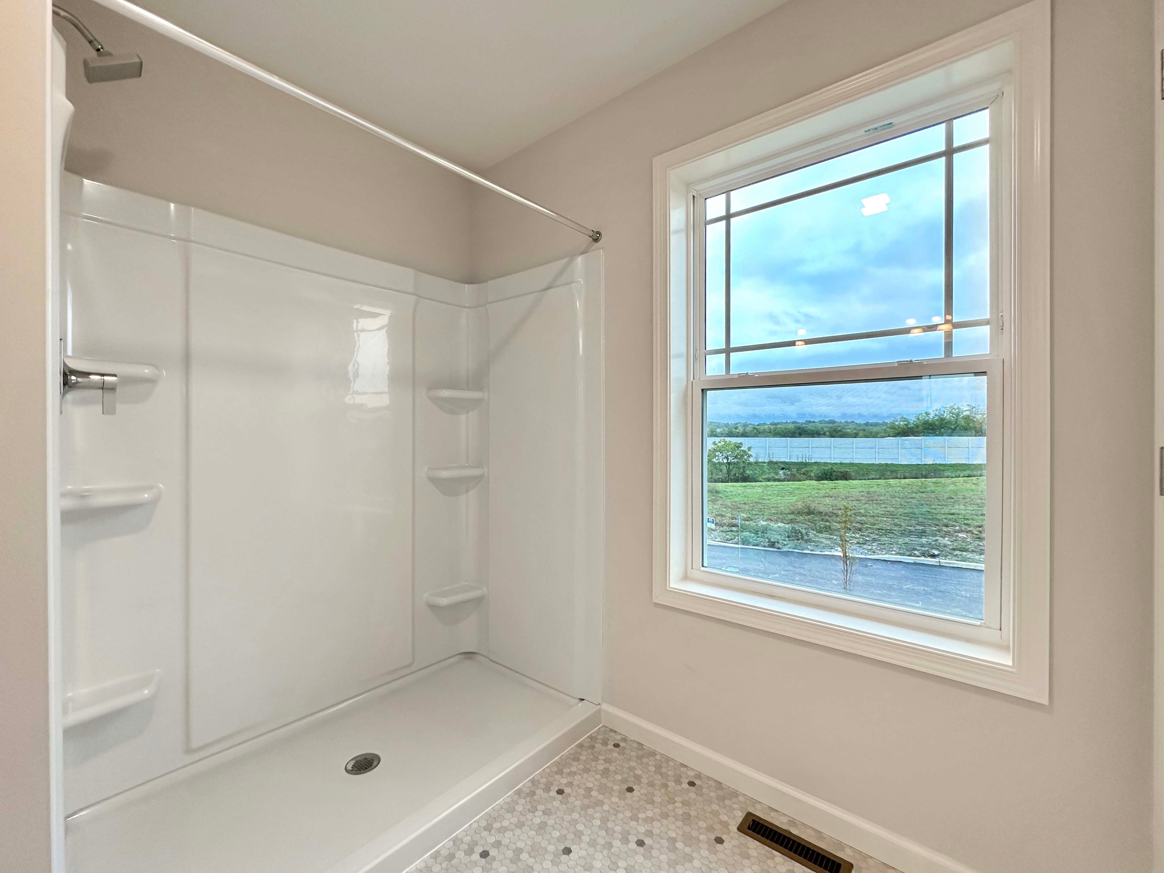 Spacious owner's bath with a walk-in shower and large window, offering plenty of natural light and scenic views.