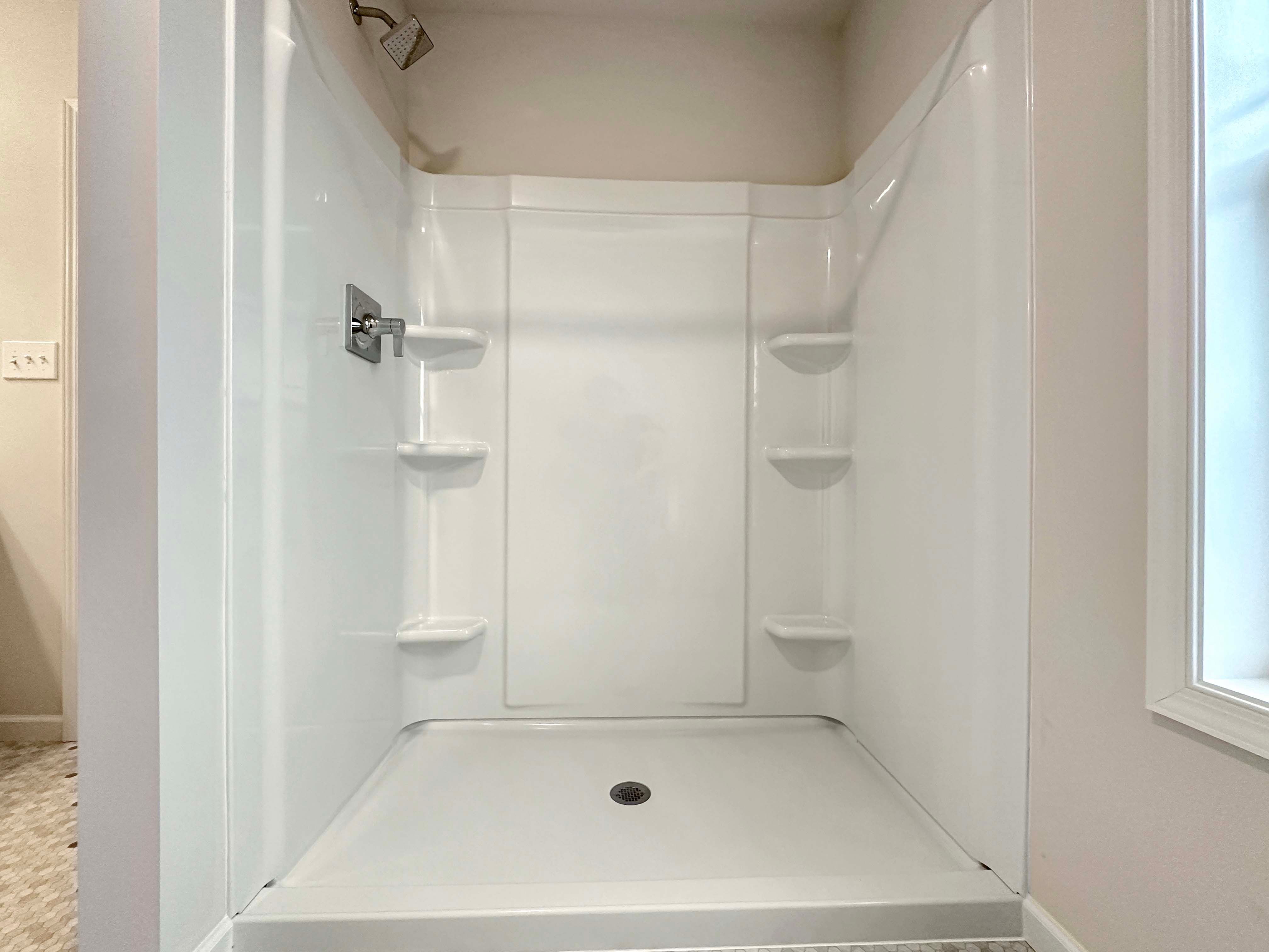 Large walk-in shower with a wide window view, located in the bright owner's bathroom.