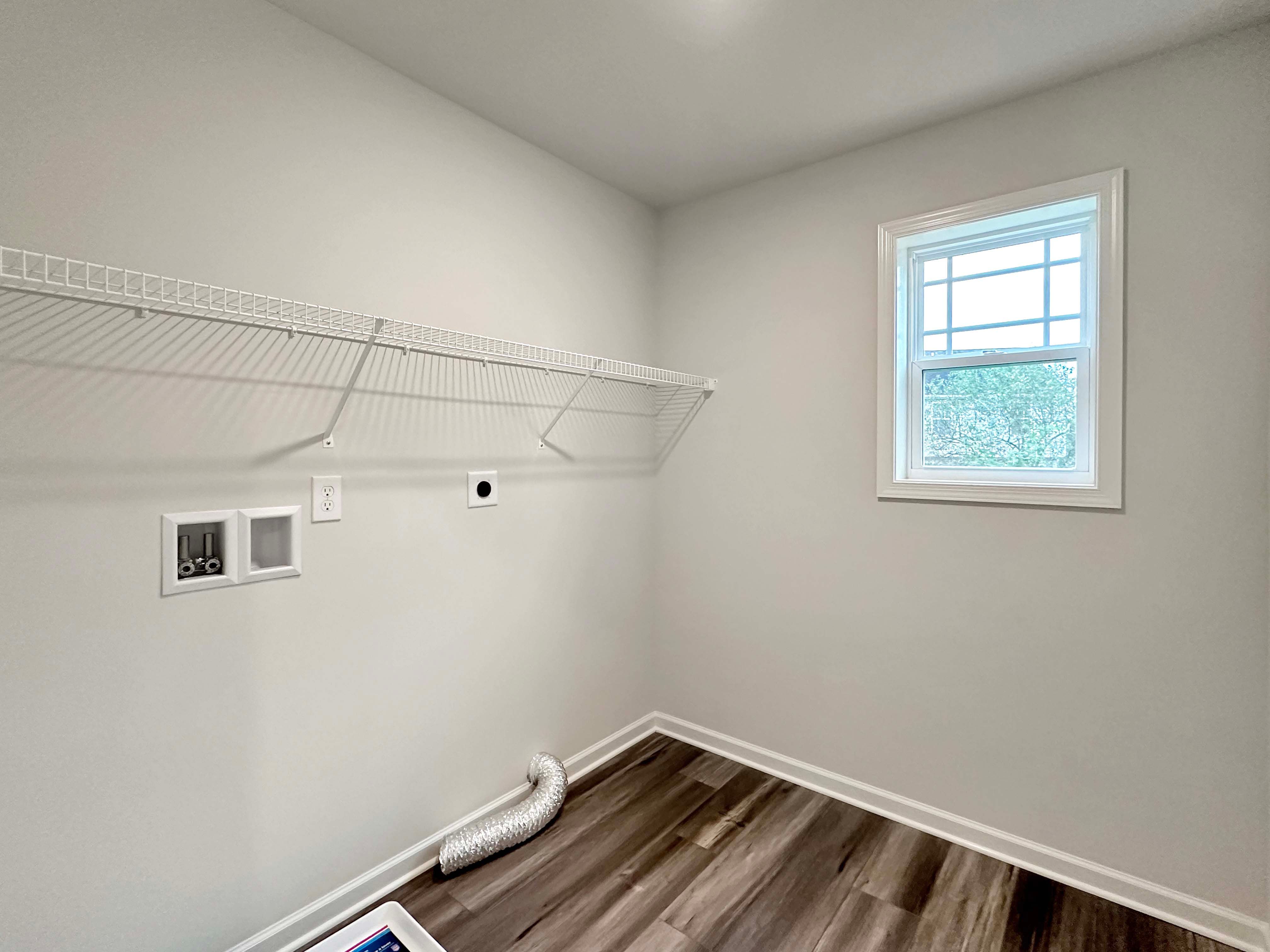 Laundry room featuring white wire shelving, a large window, and hookups for washer and dryer.