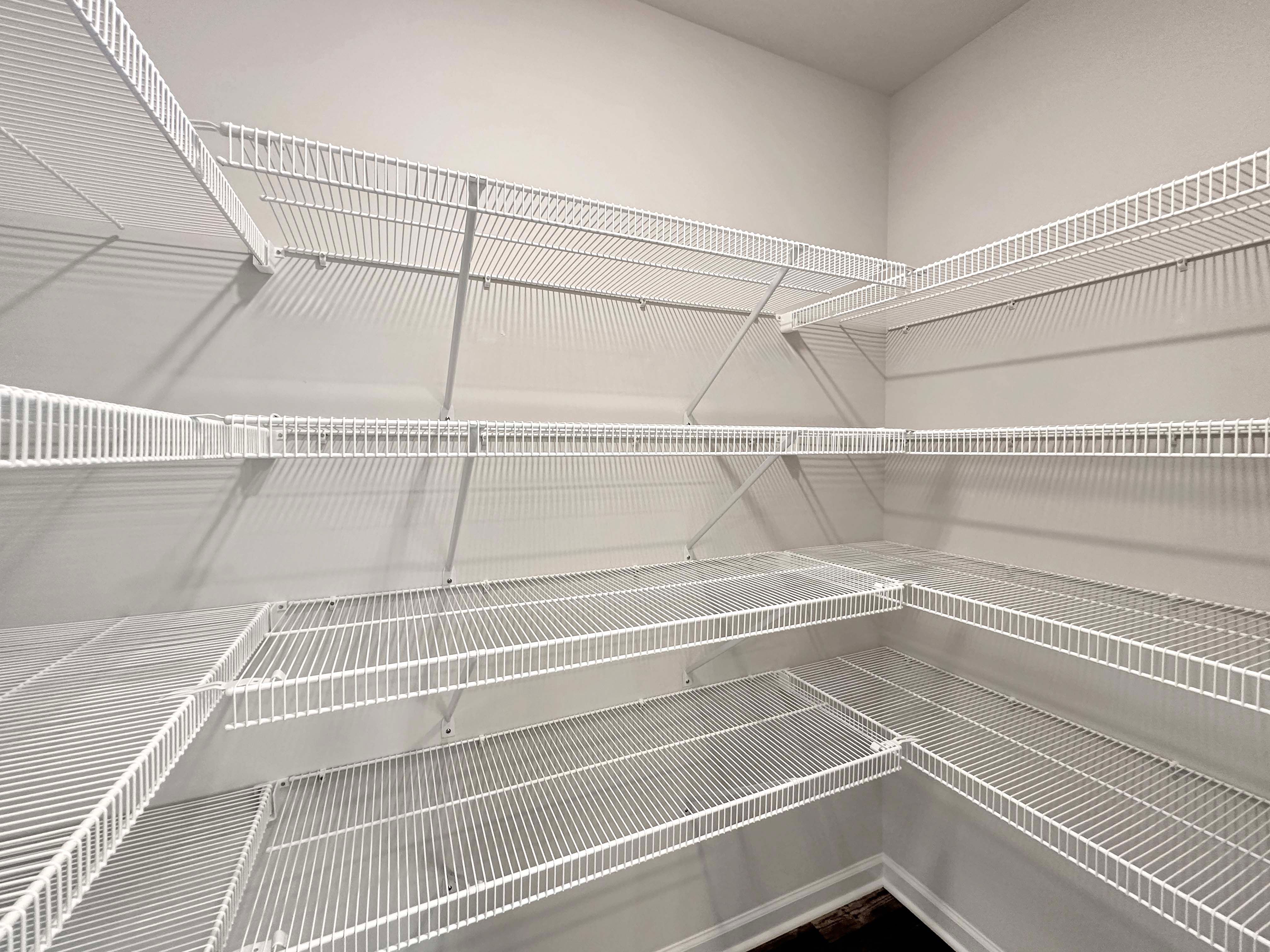 Walk-in pantry with multiple white wire shelves for storage.