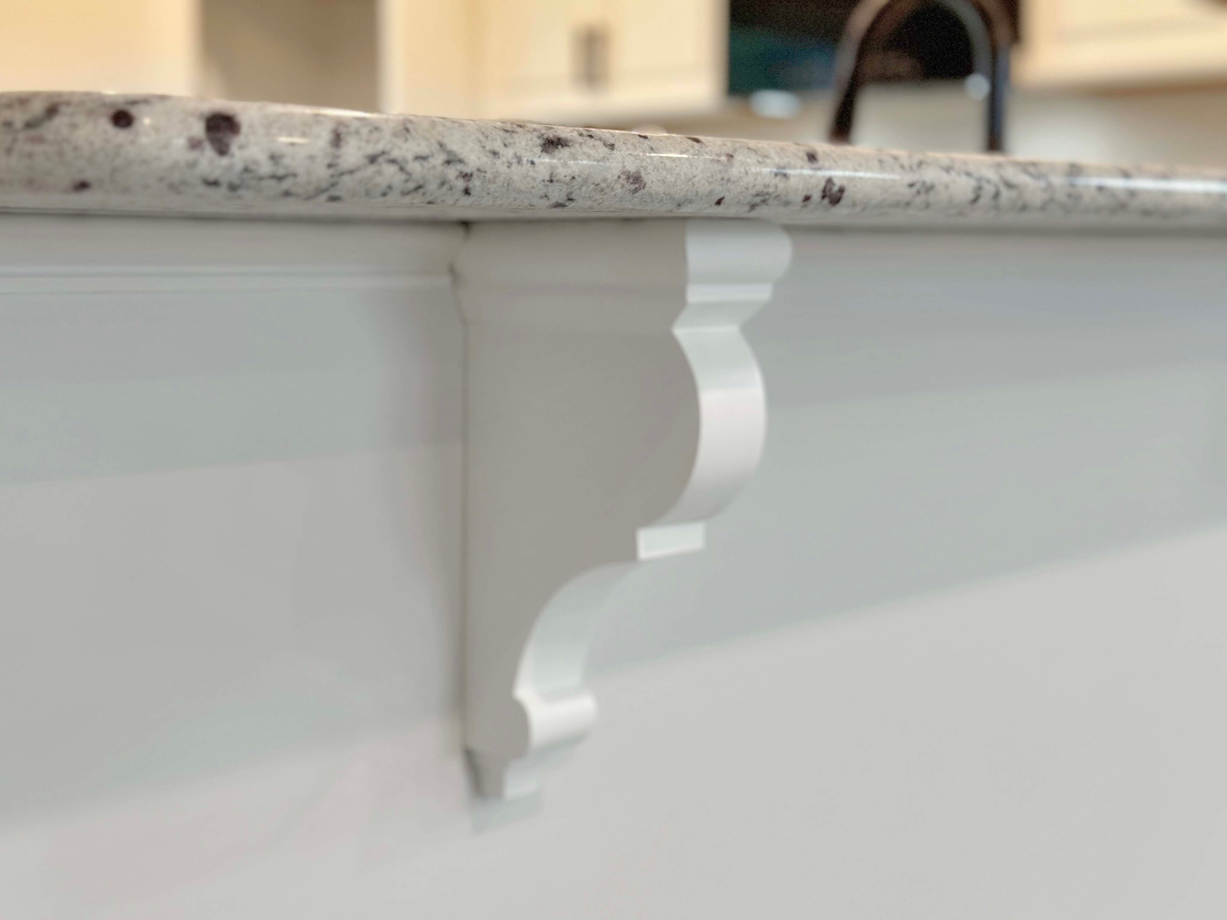 Close-up of decorative white corbel under granite kitchen countertop, adding stylish detail to the kitchen design.