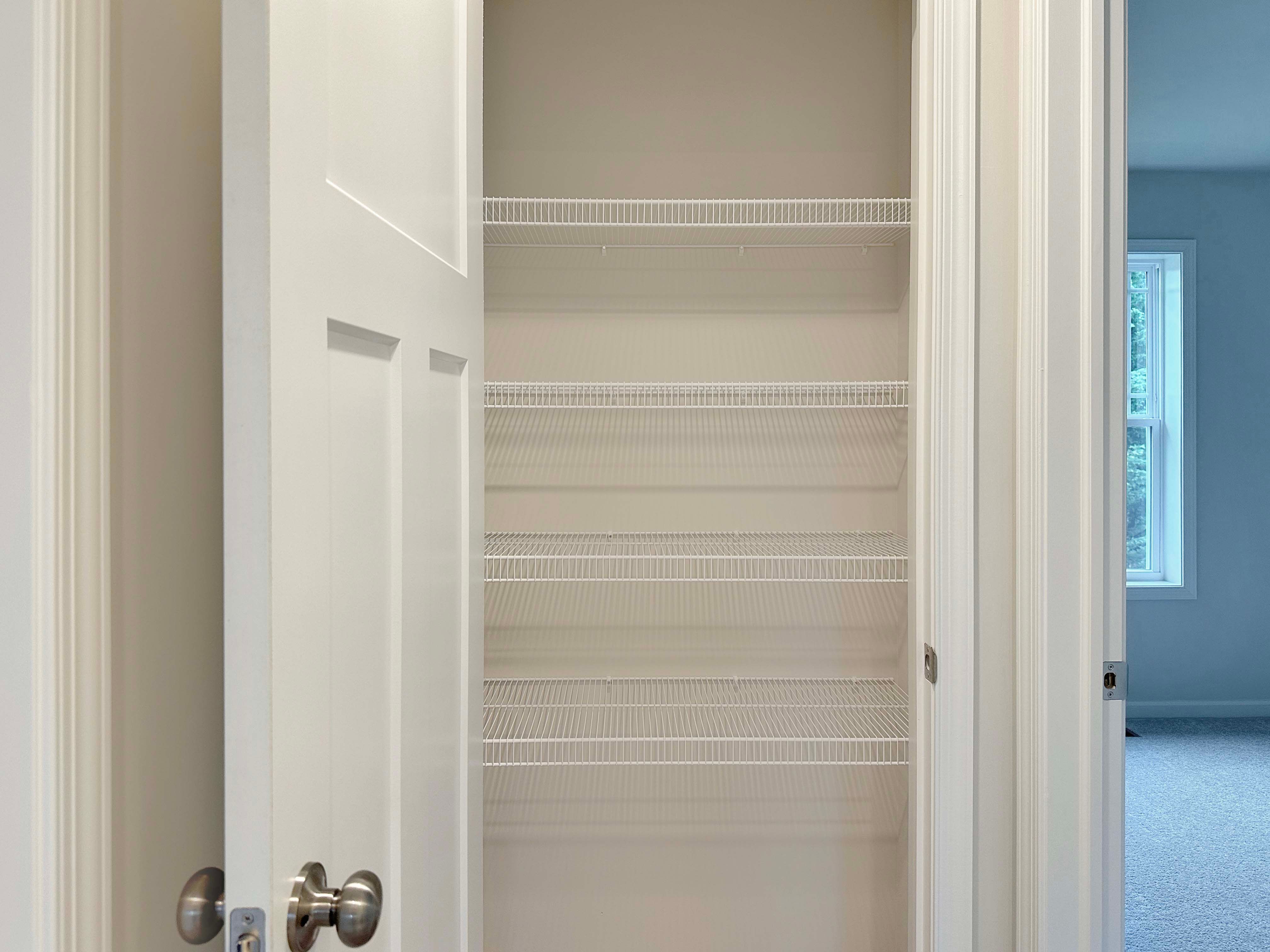 Linen closet with white wire shelving, perfect for storing towels, linens, and household supplies.