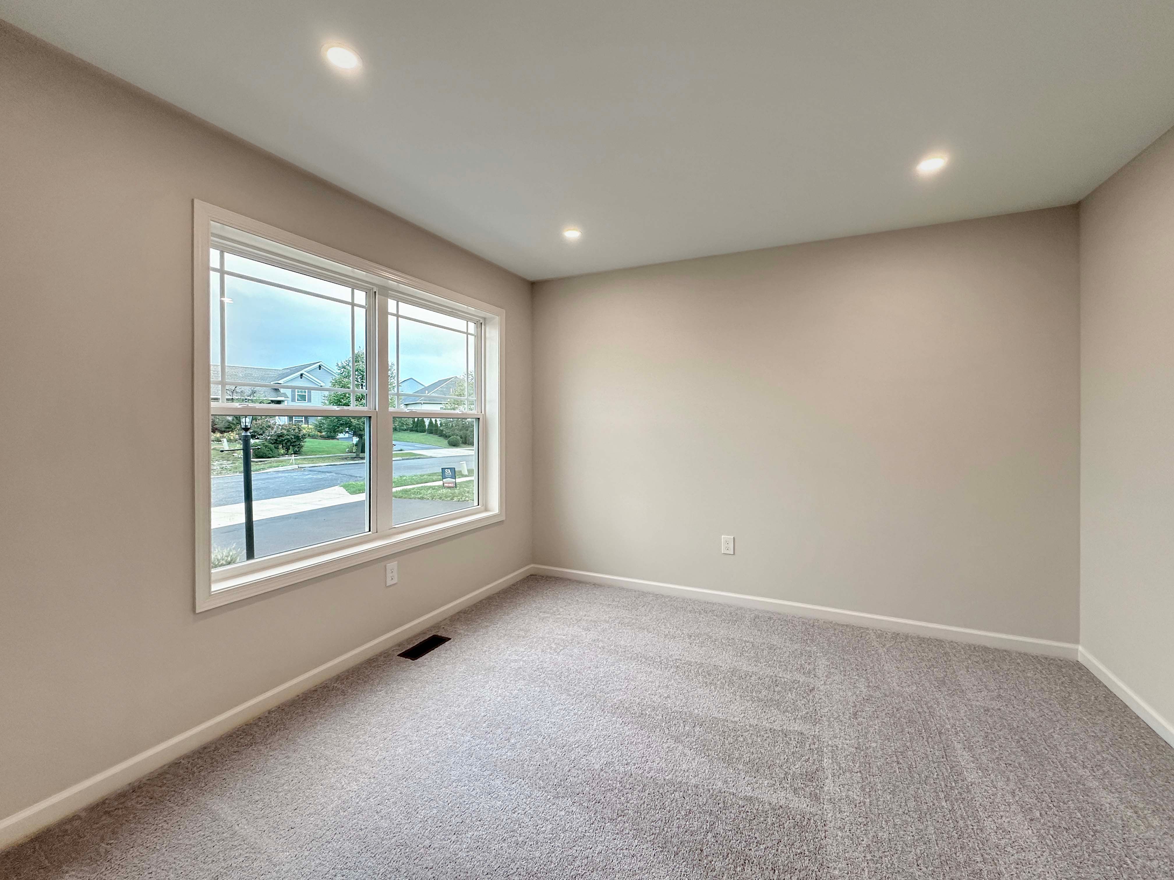 Unfurnished den with large window facing the front of the home, recessed lighting, and carpet flooring.