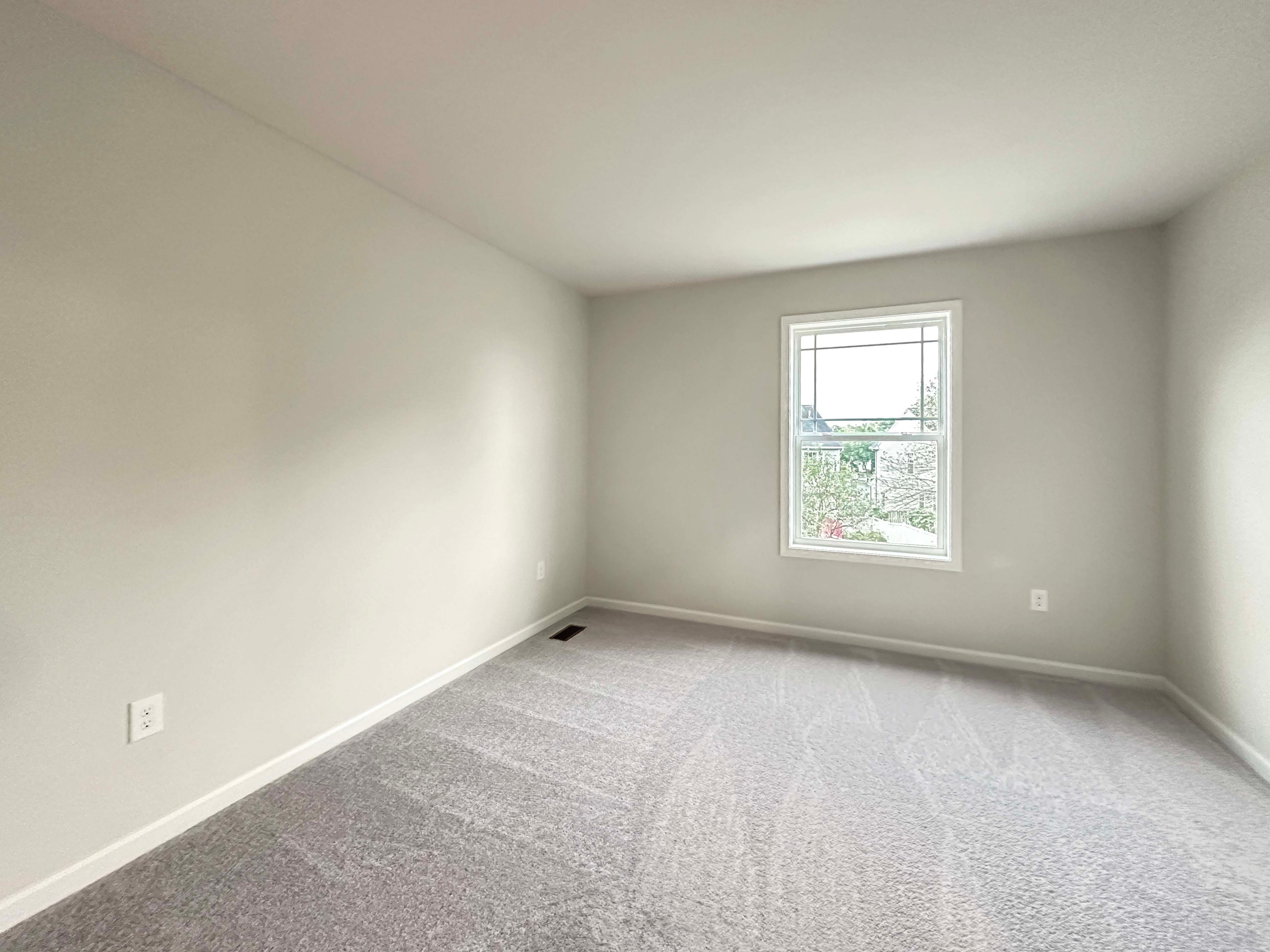 Bedroom with large window, carpet flooring, and plenty of natural light, offering a peaceful view outside.