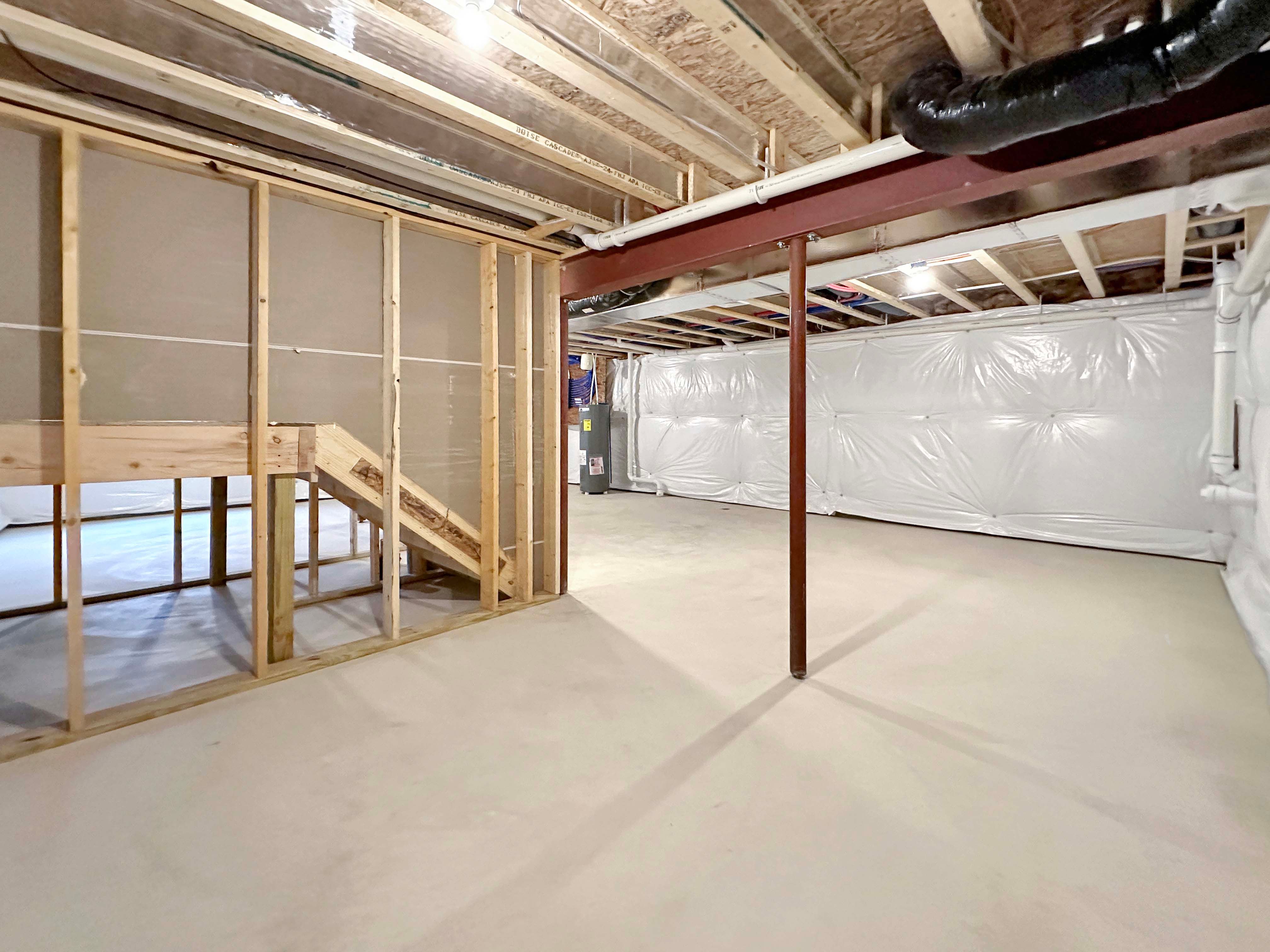 Basement with exposed framing, wooden stairs, and a concrete floor, offering plenty of space