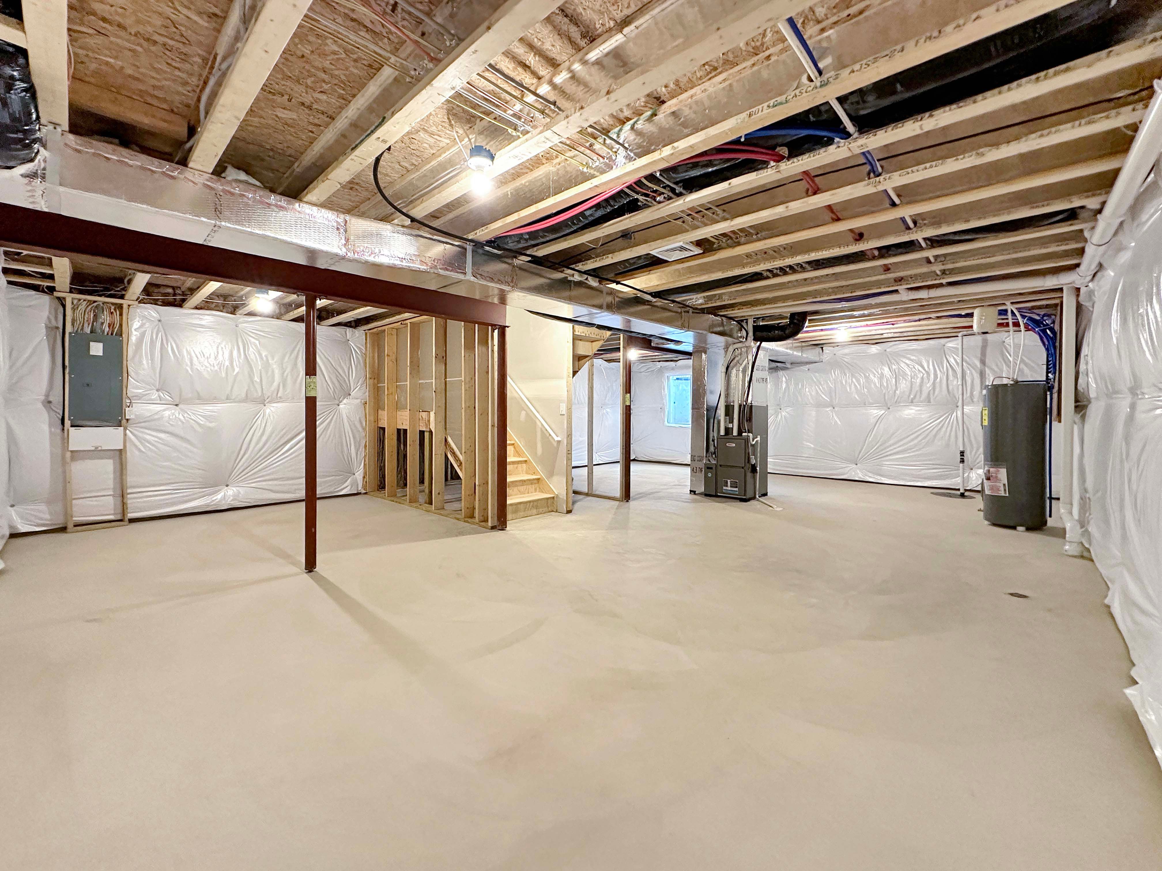 Unfinished basement with exposed ceiling beams, steel support columns, and a large open layout