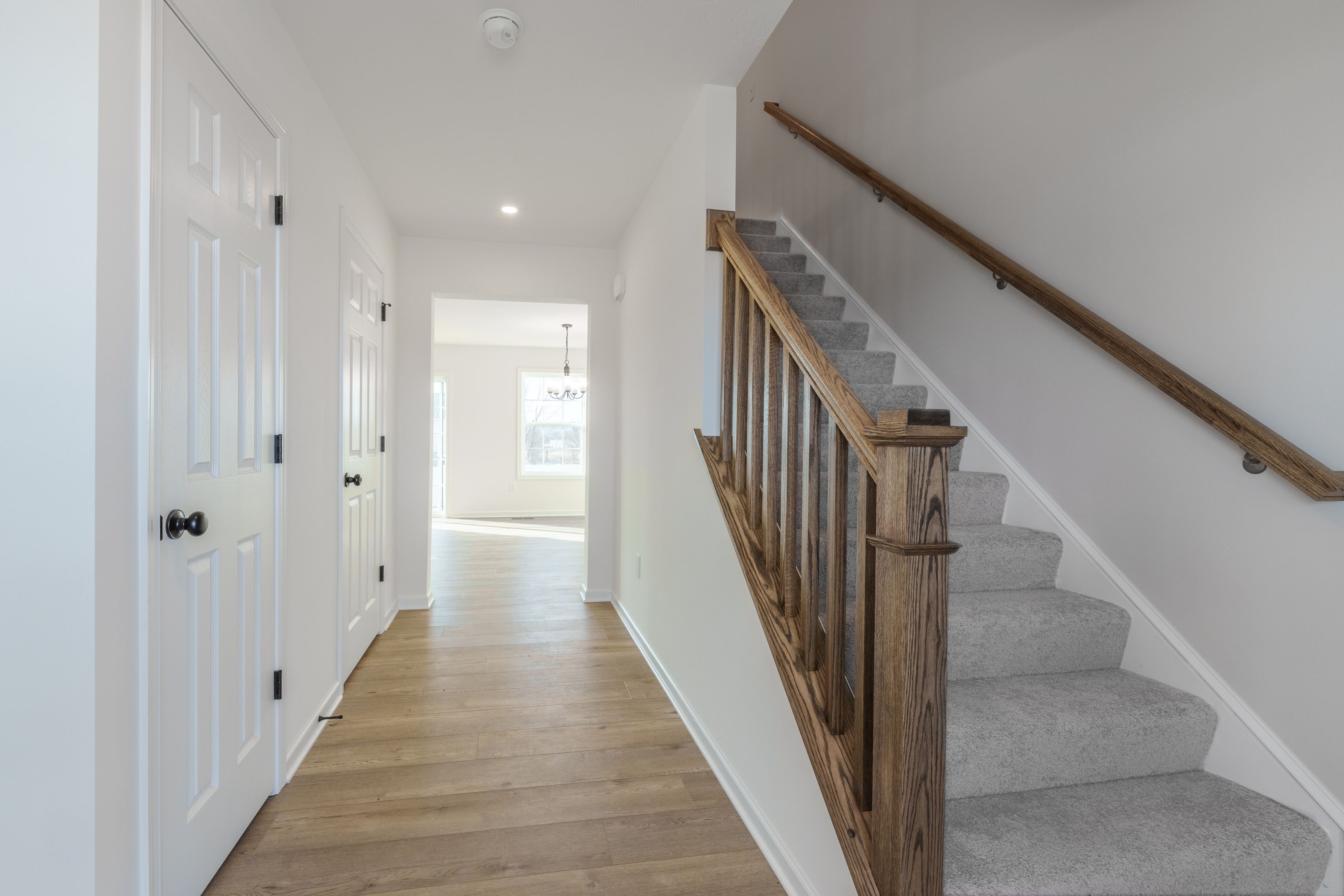 Spacious foyer with neutral walls, light carpet flooring, and a clear view into the connected living area.