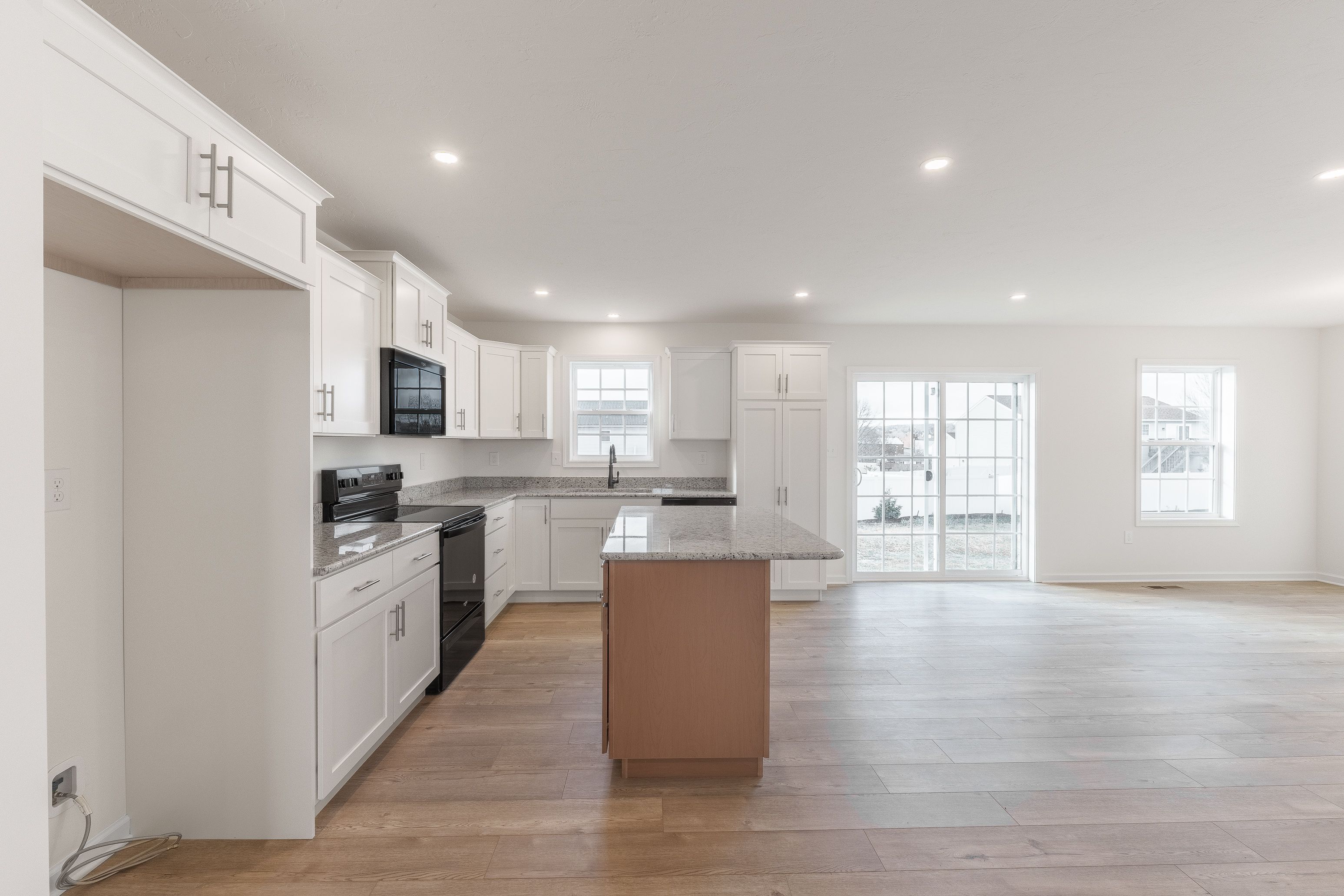 Modern kitchen with white cabinets, black stainless steel appliances, granite countertops, and a central island with extra storage.