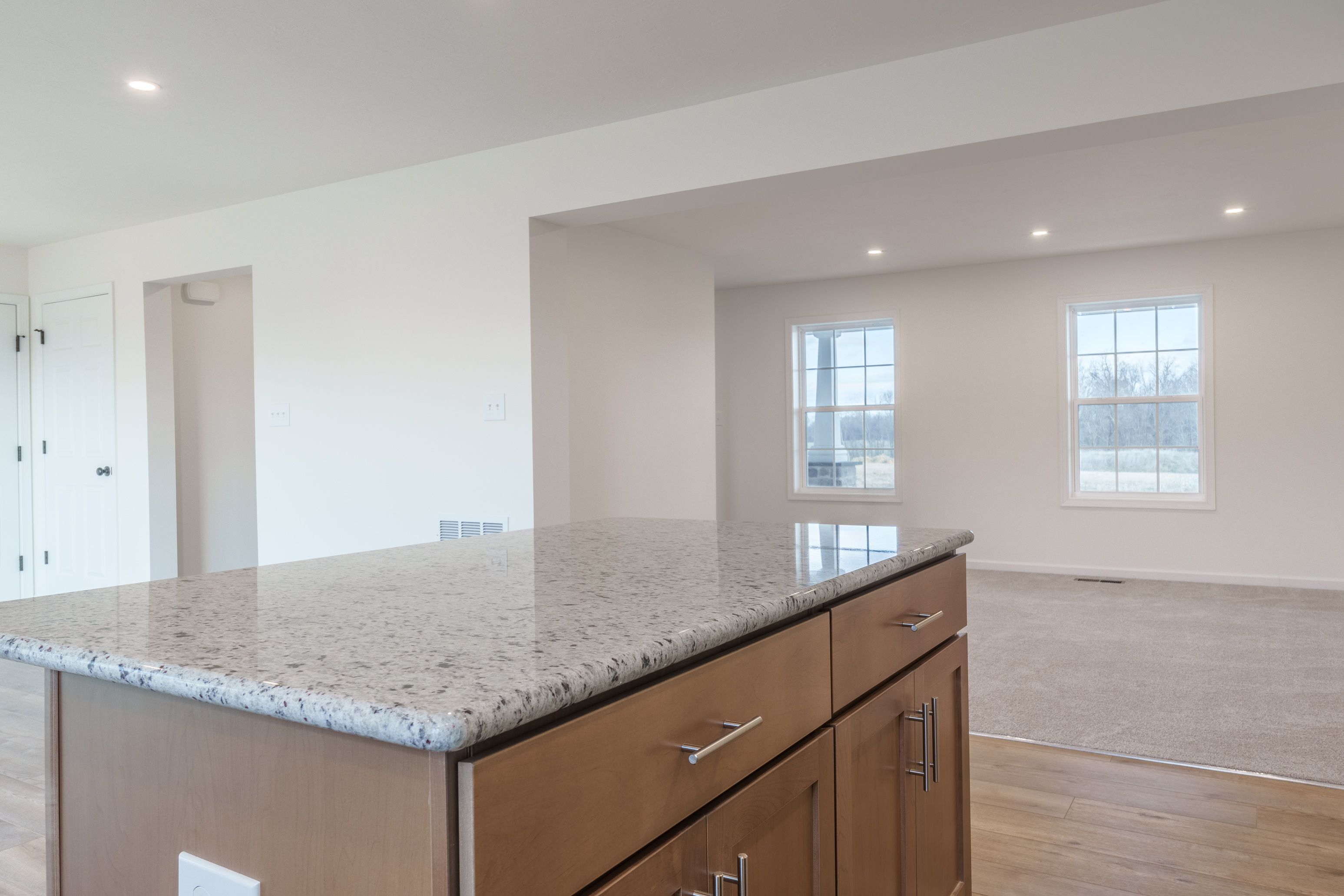 Modern kitchen with a large central island, white cabinets, granite countertops, and a bright, open feel.
