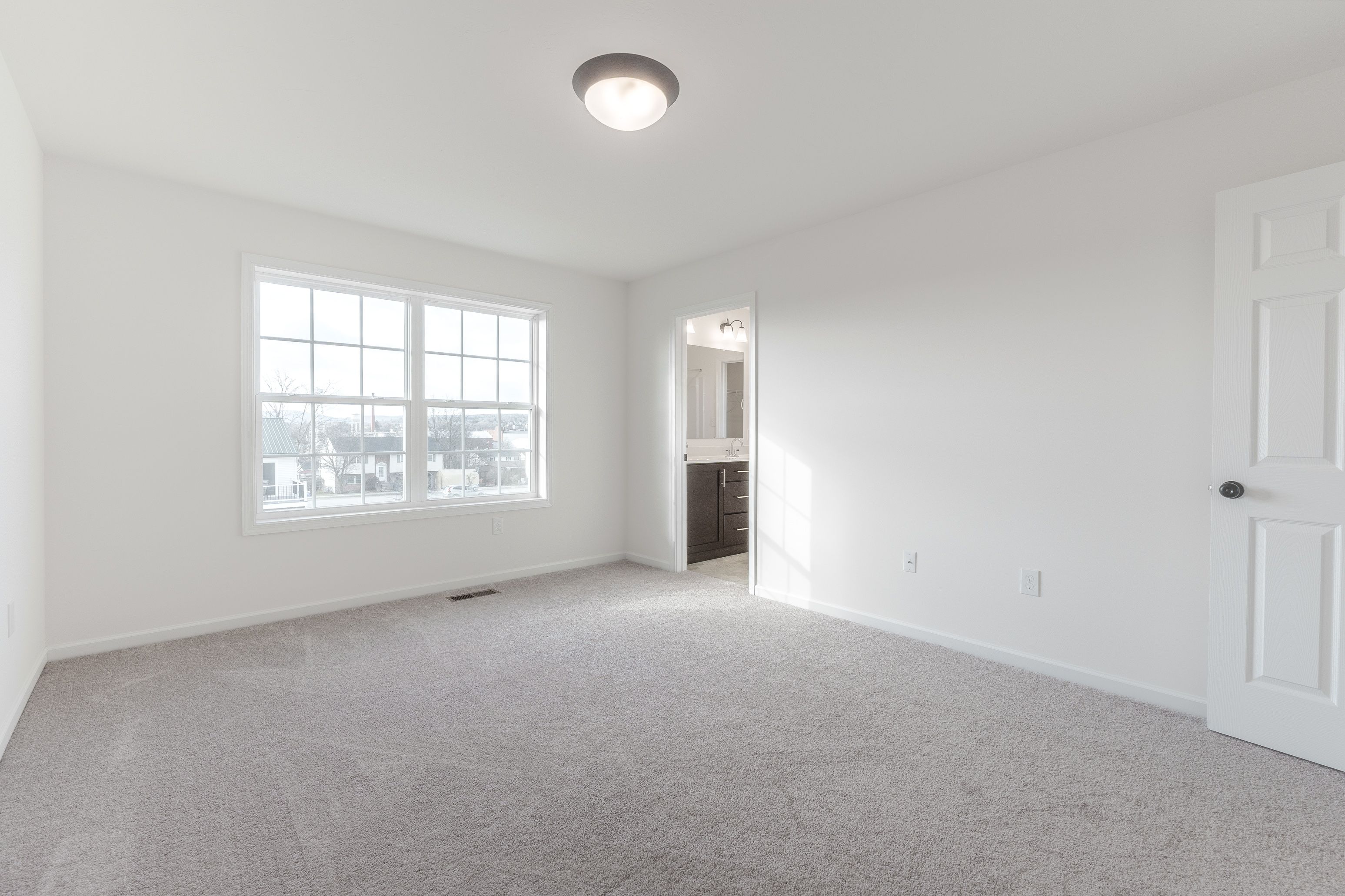 Owners bedroom with soft carpet, a large window providing natural light, and a simple design.