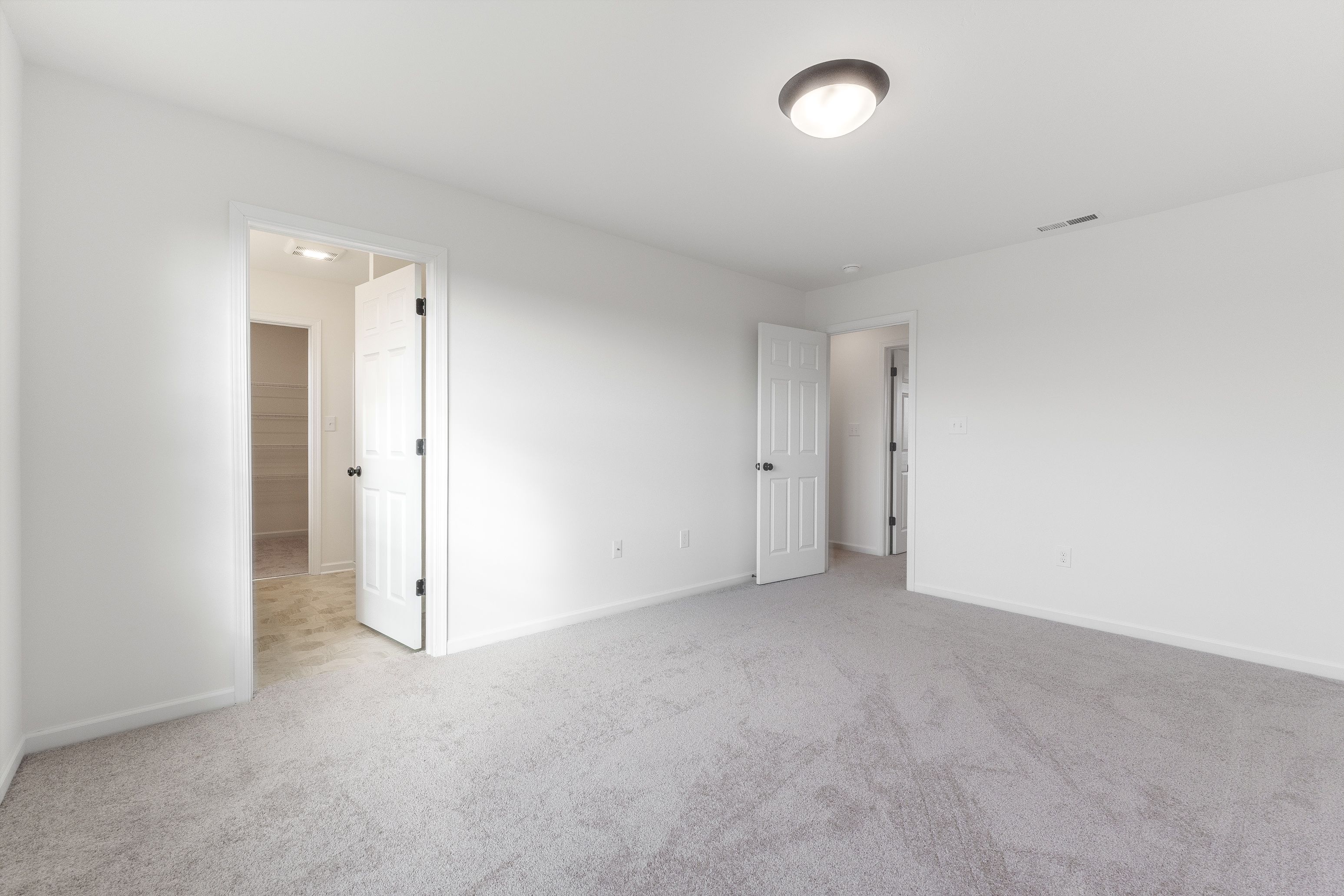 Owners bedroom with light carpet, a window for natural light, and neutral-colored walls.