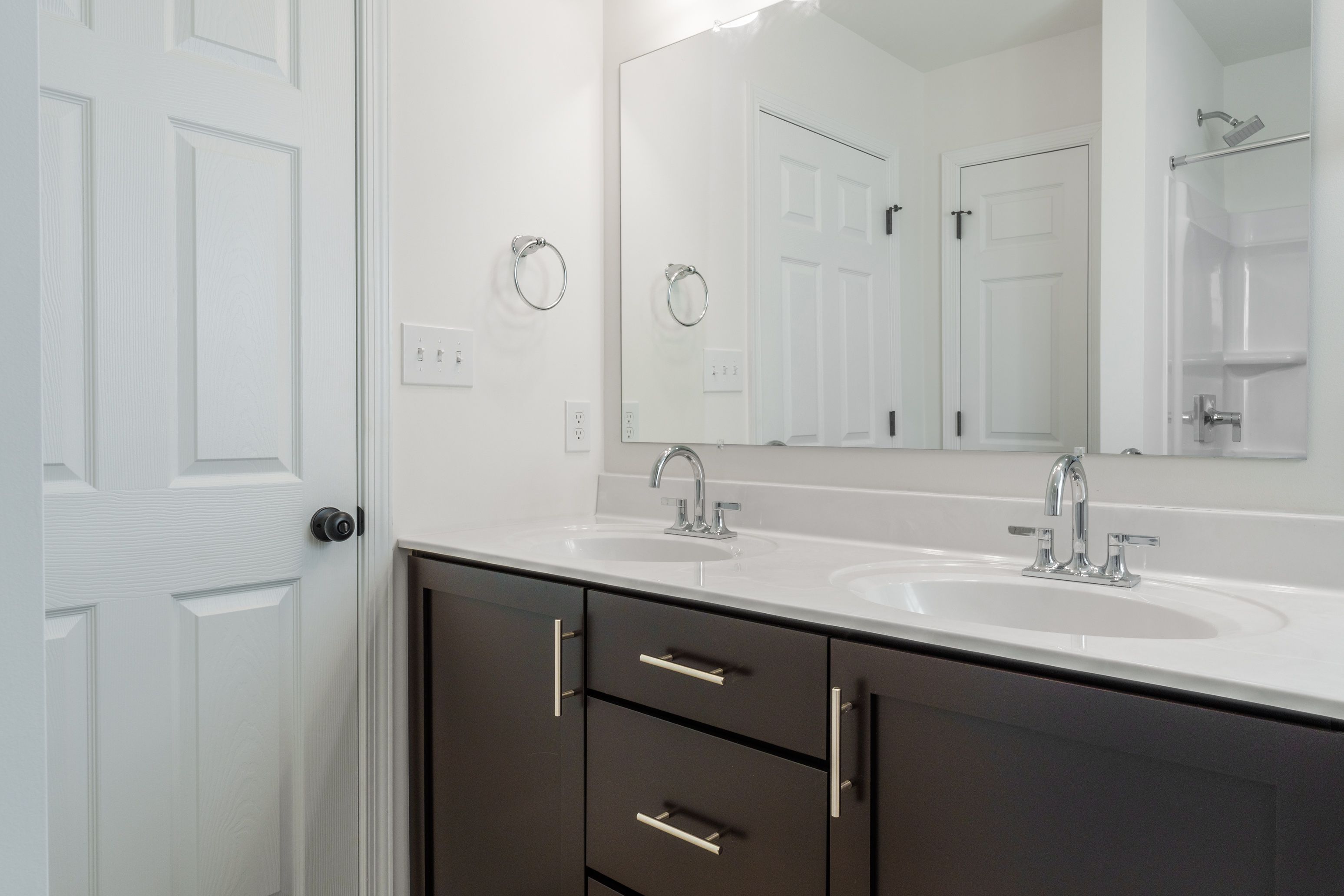 Owners bathroom with double sinks, modern fixtures, a shower, and a large mirror.