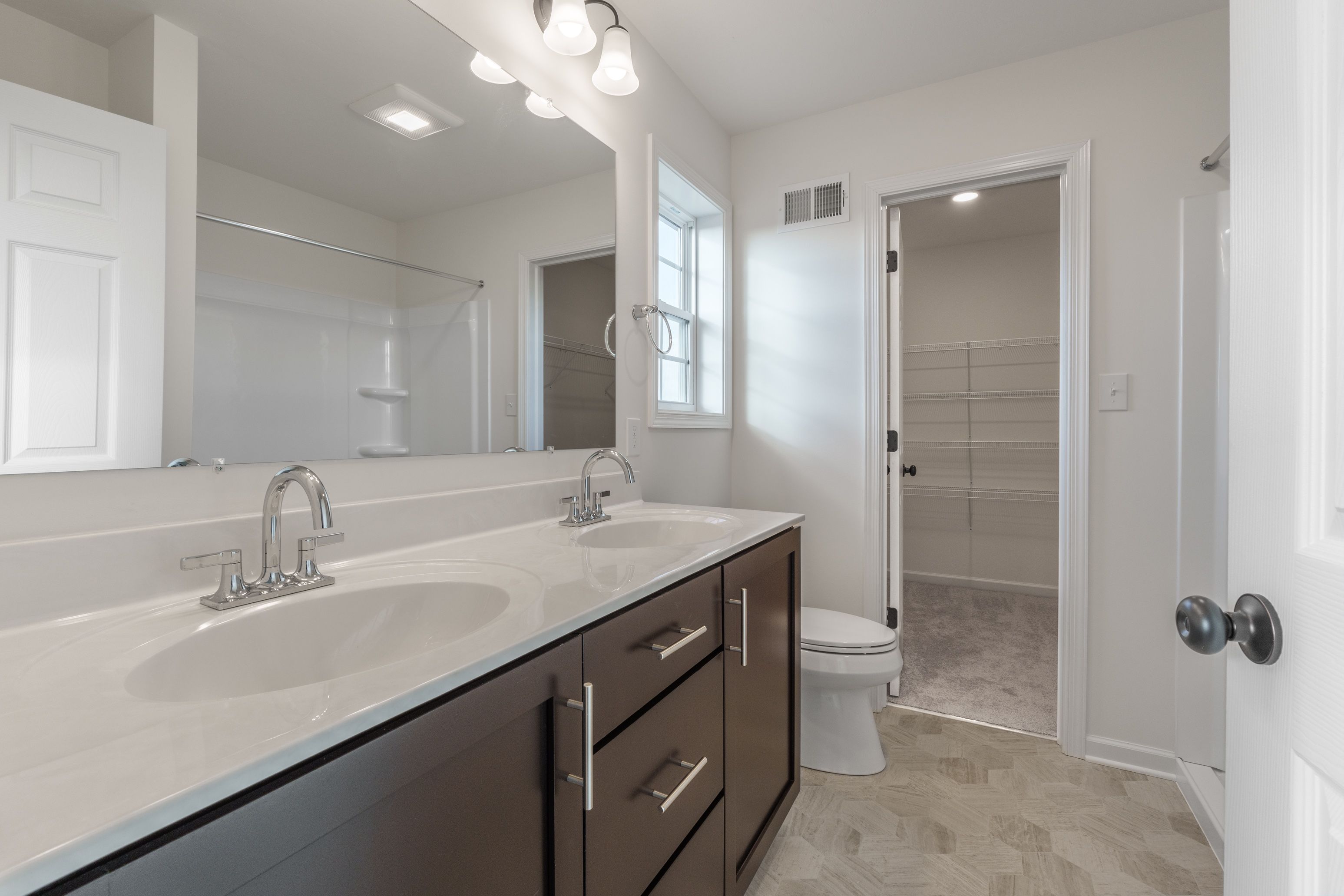 Owners bathroom with a double vanity, mirrors, and a bathtub/shower combo with natural light.