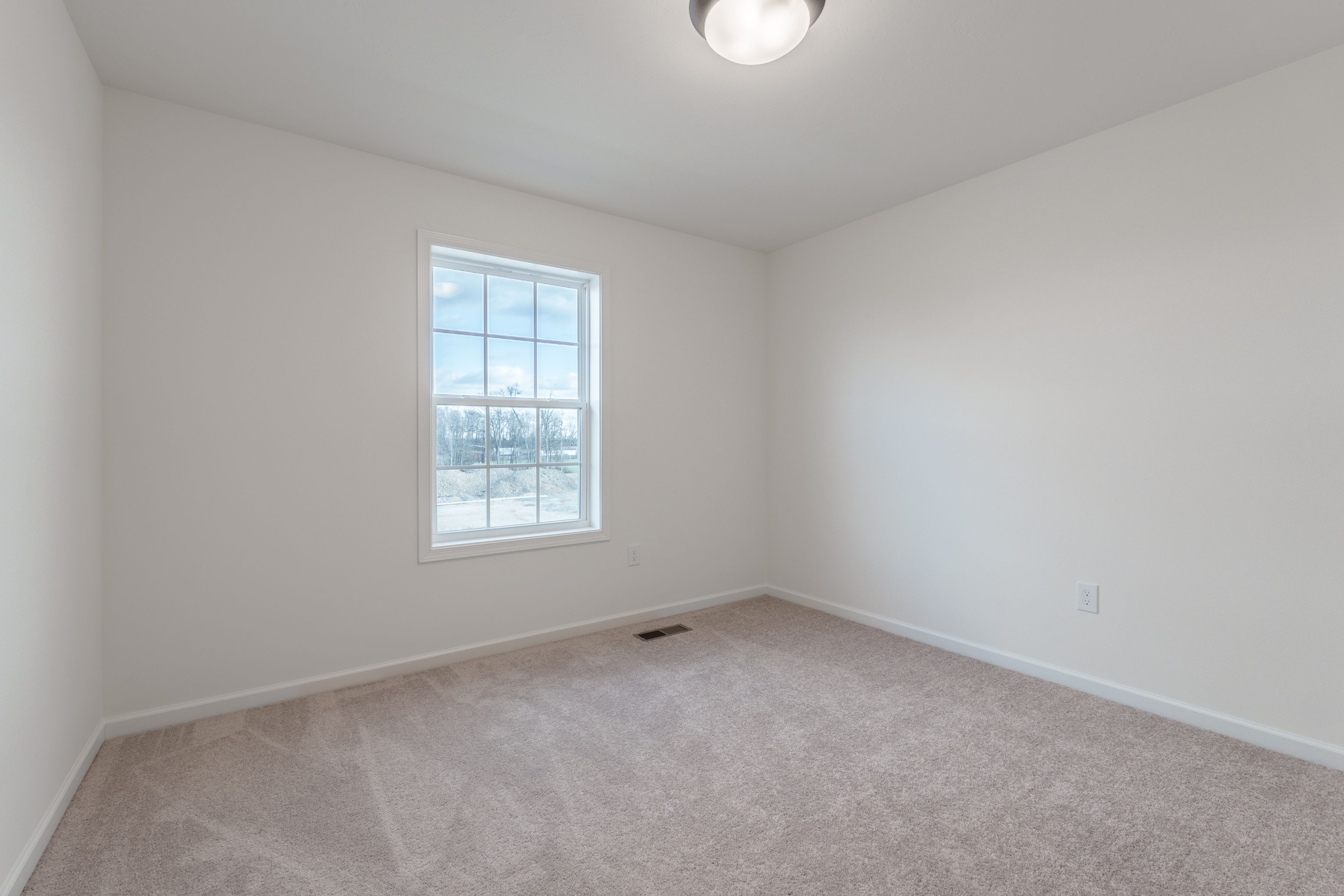 Bedroom featuring light carpet, a window letting in natural light, and neutral walls.