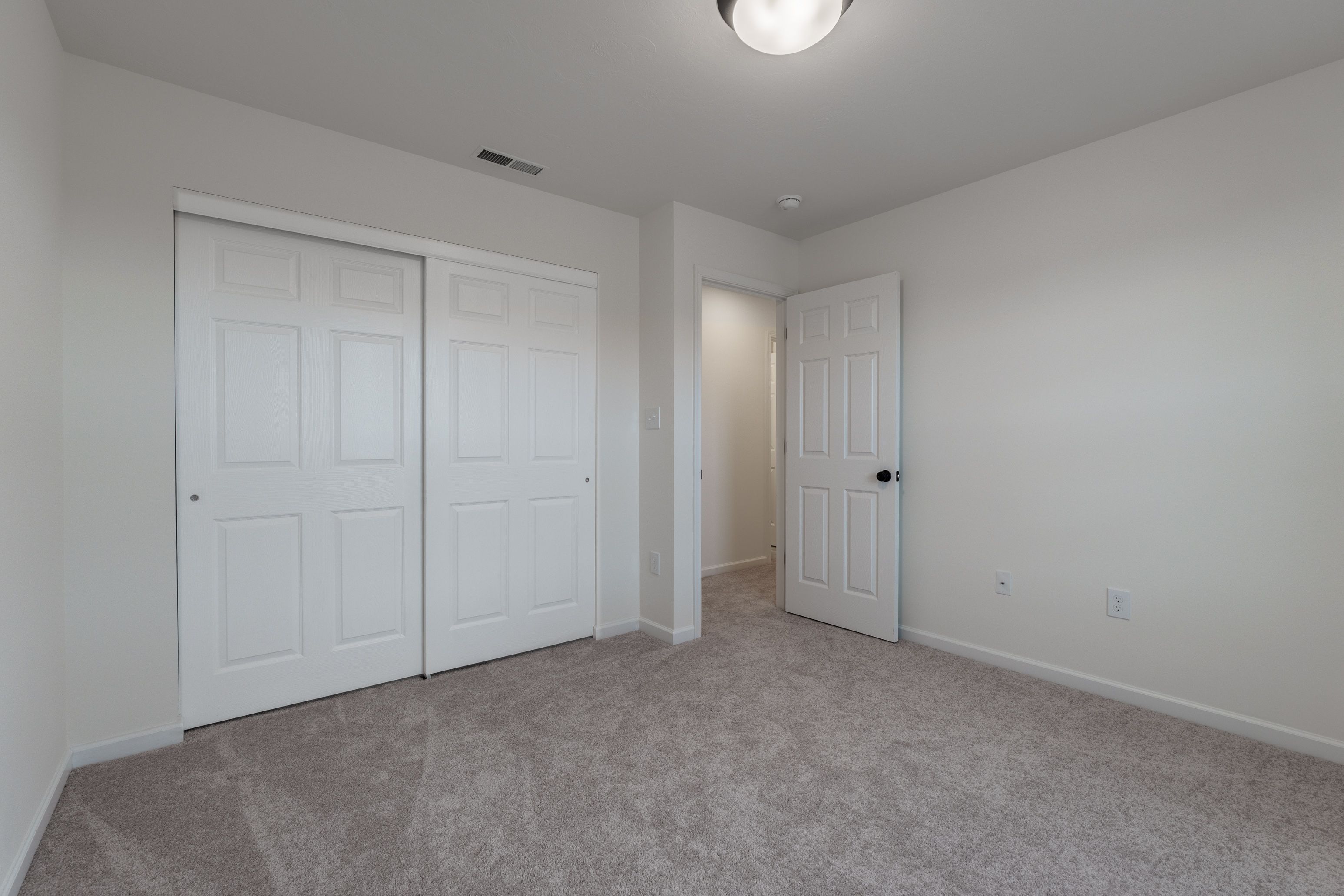 Bedroom with light carpet, a closet, and a window offering a view of the outside.