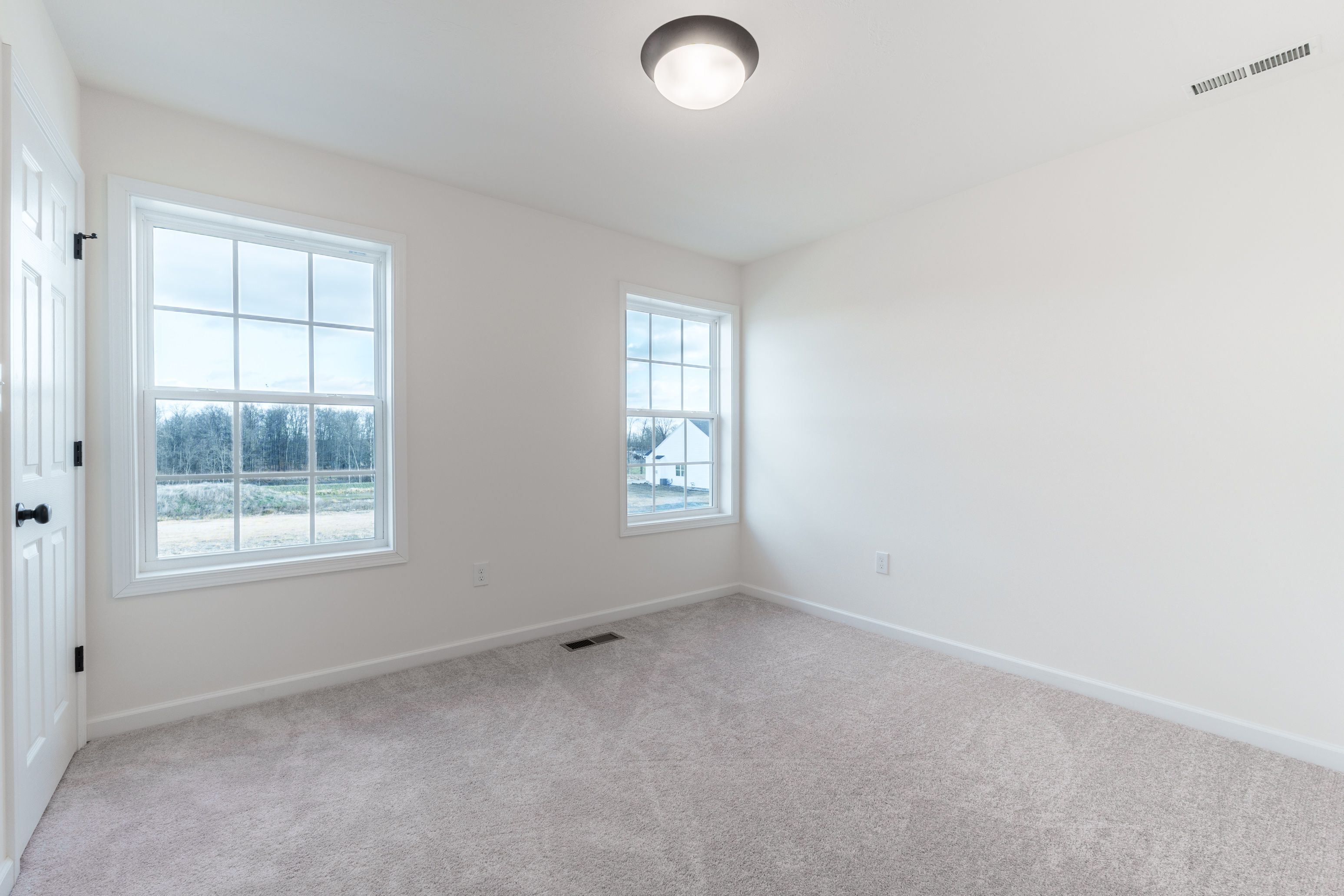 Bedroom with light carpet, a large window for natural light, and a neutral color palette.