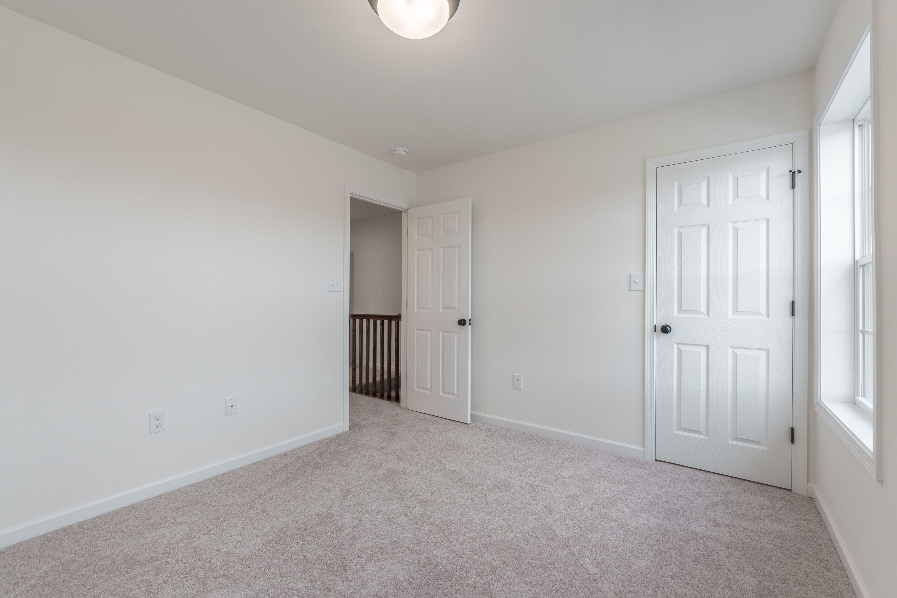 Bedroom with light carpet, a closet, and a view through the window.